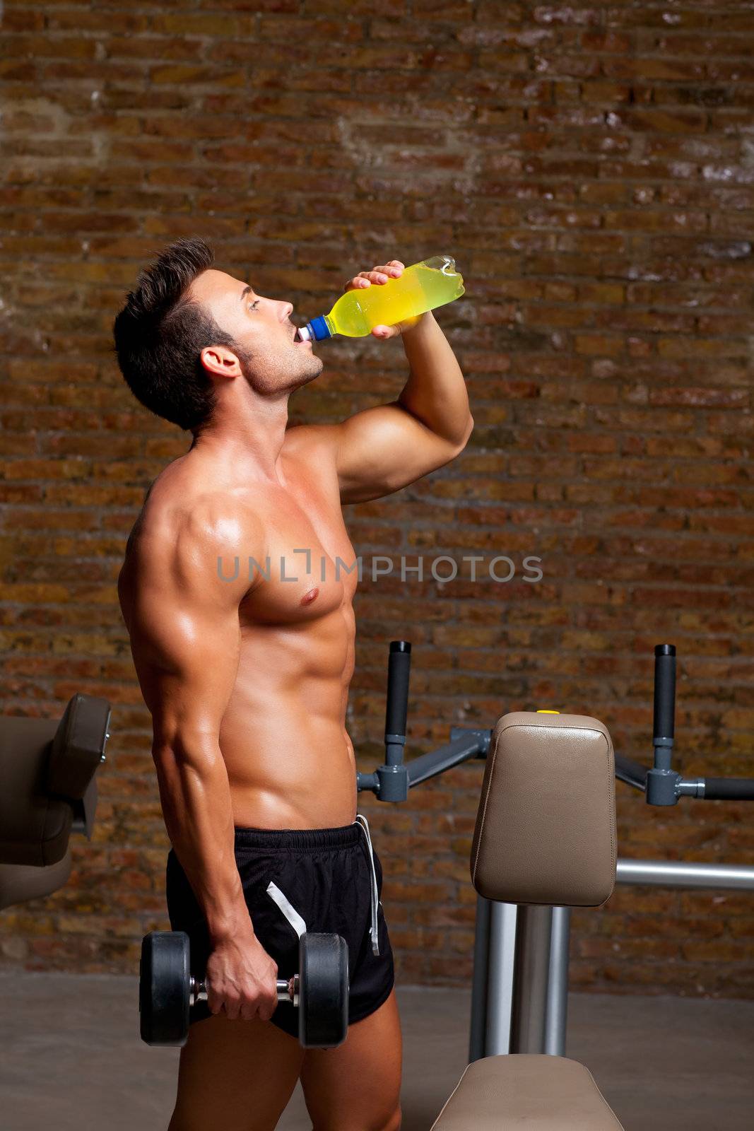 muscle shaped man at gym relaxed drinking energy drink