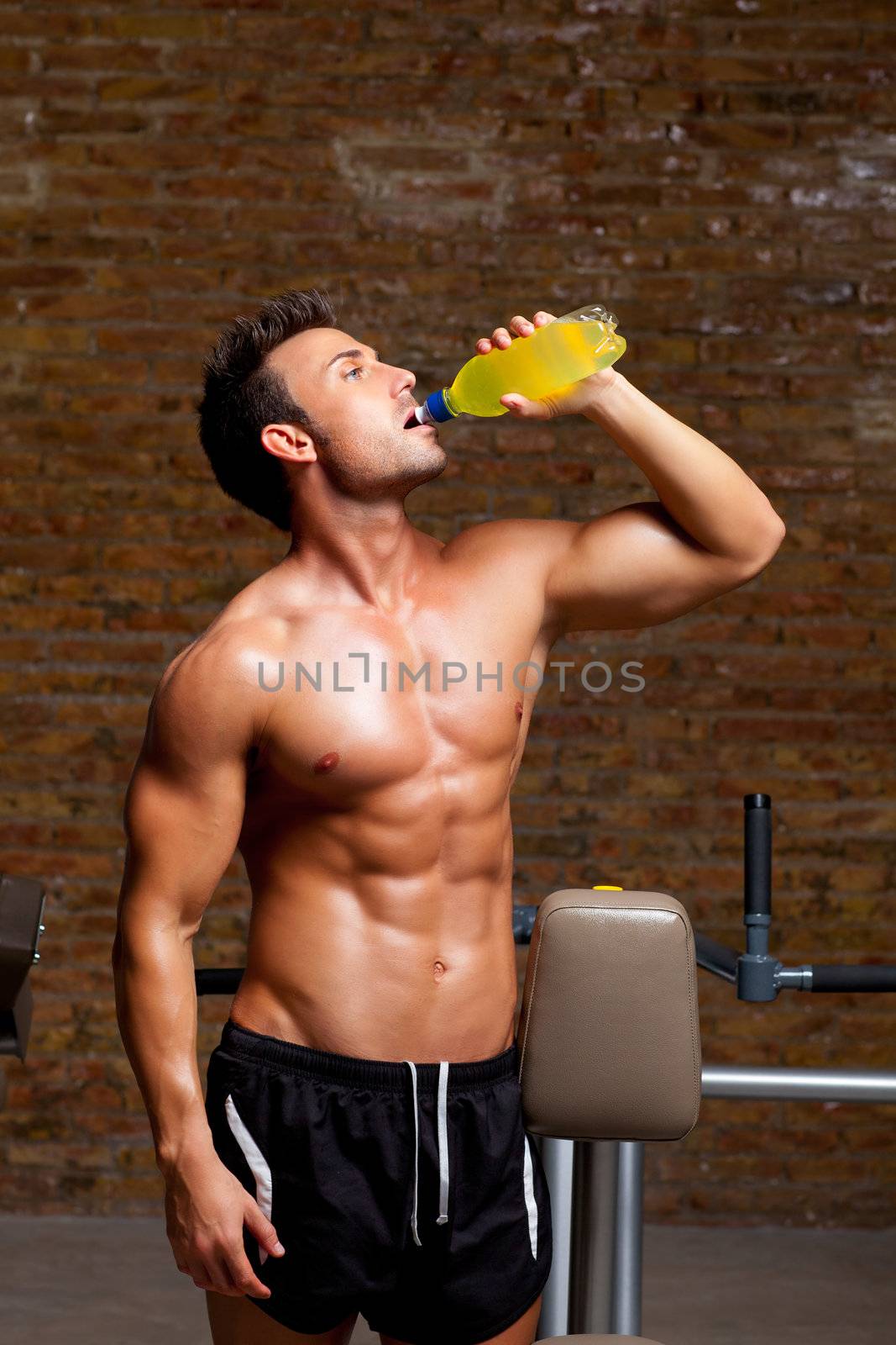 muscle shaped man at gym relaxed drinking energy drink