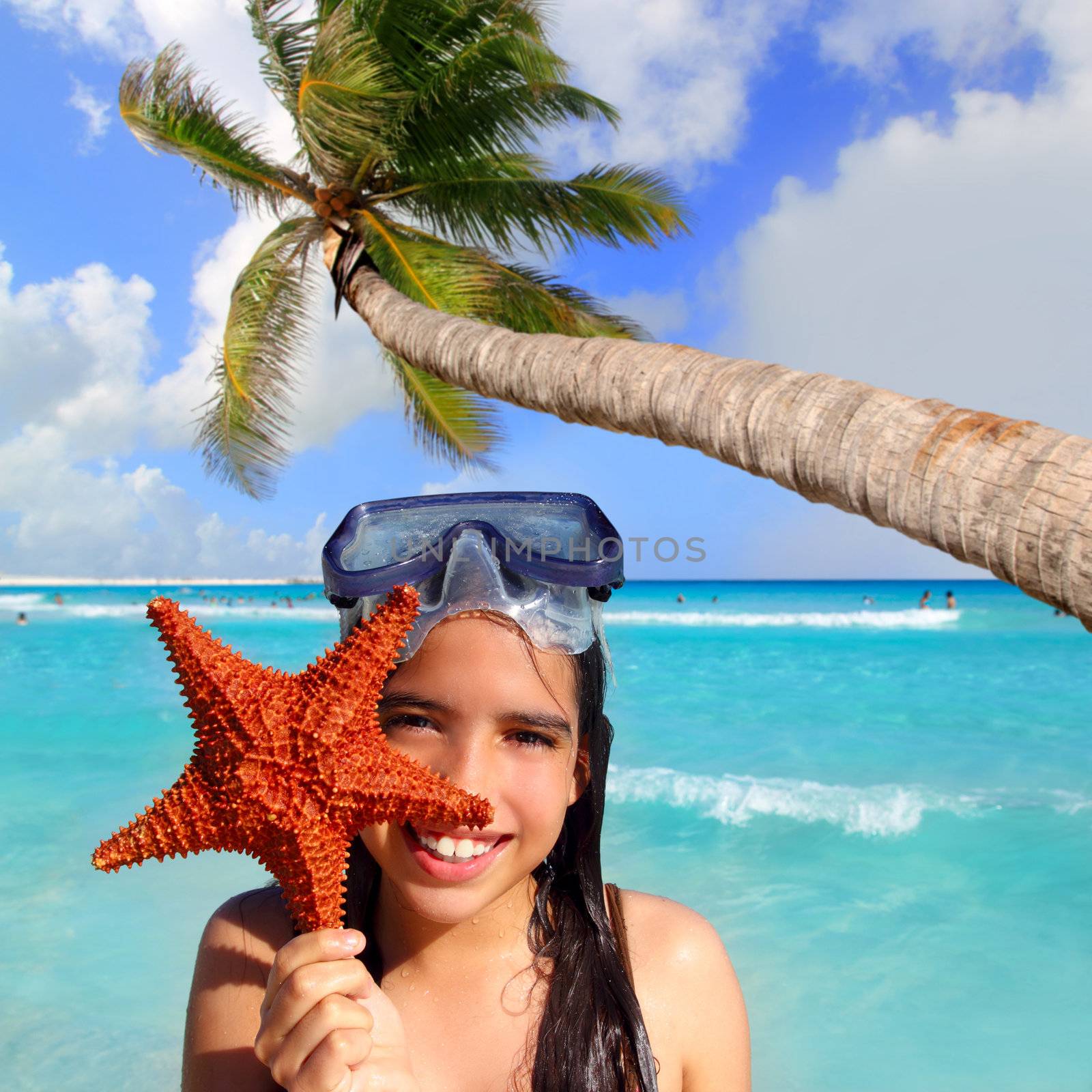 latin tourist girl holding starfish in tropical beach