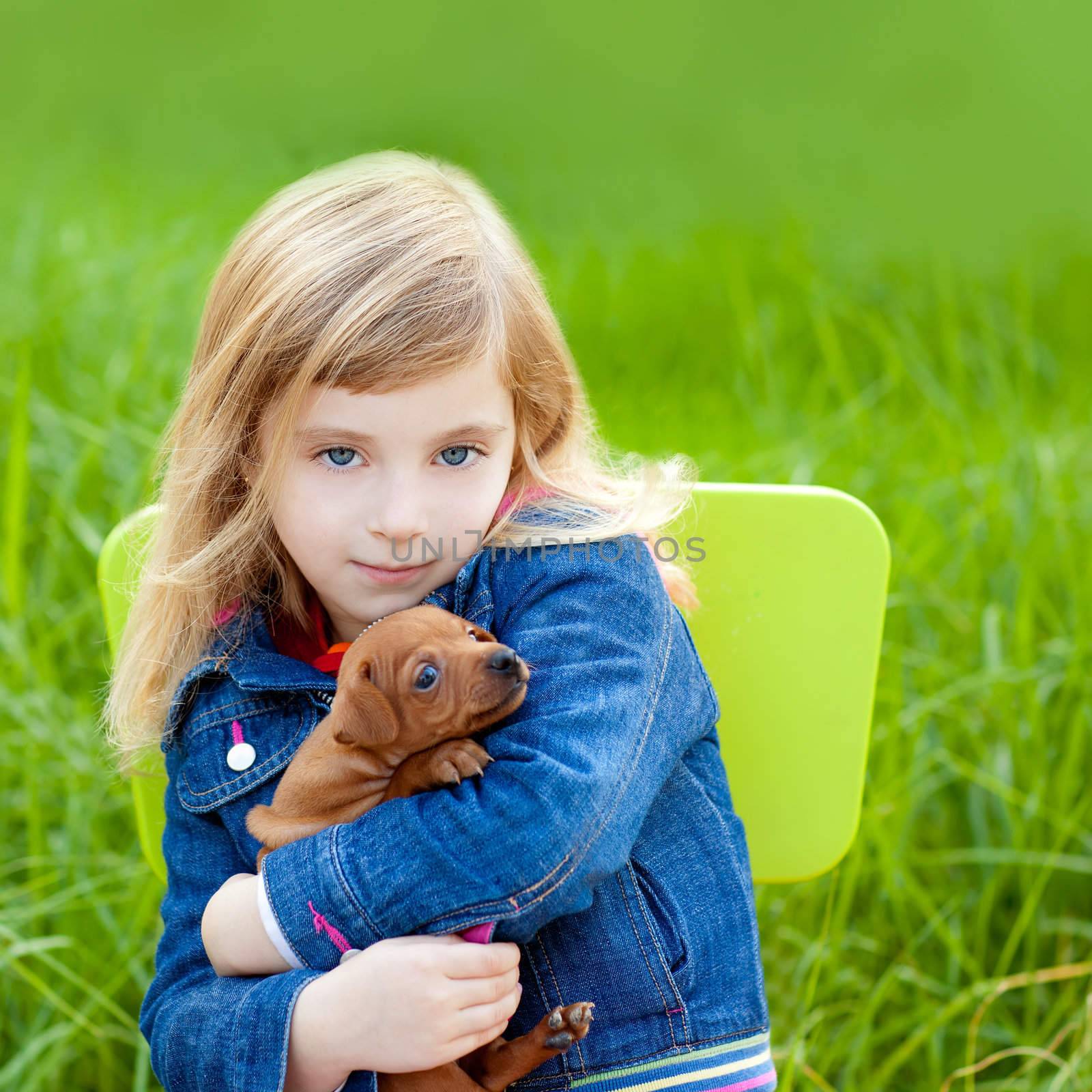 Blond kid girl with puppy pet dog sit in outdoor green grass