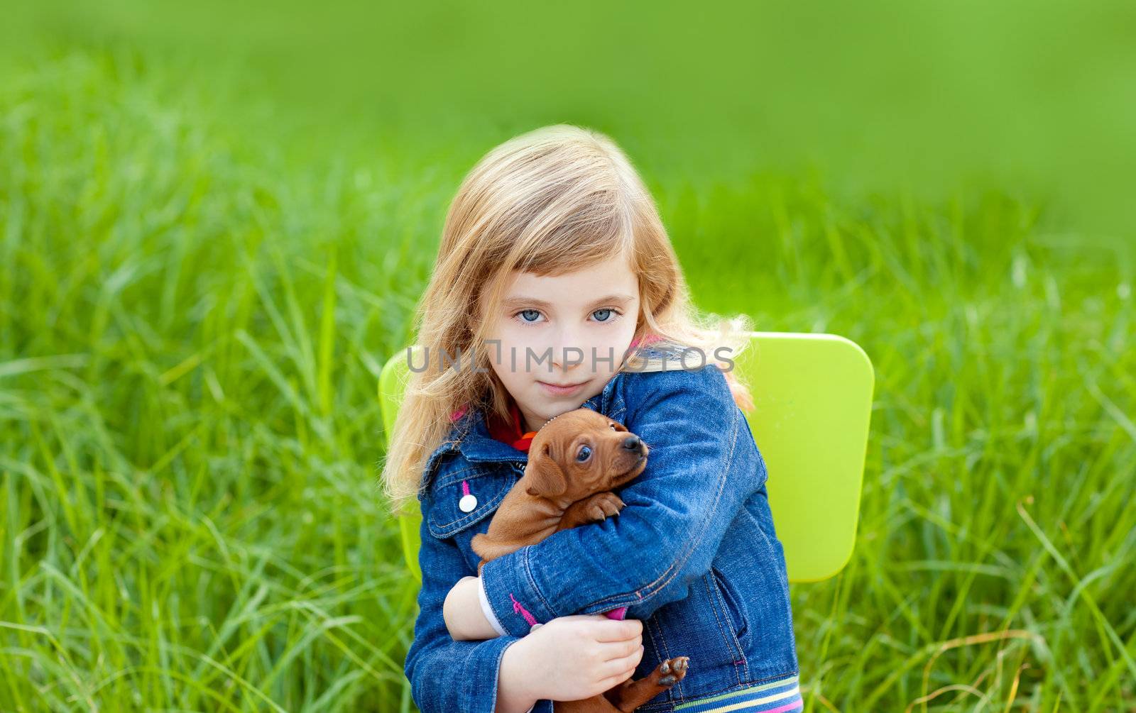 Blond kid girl with puppy pet dog sit in outdoor green grass