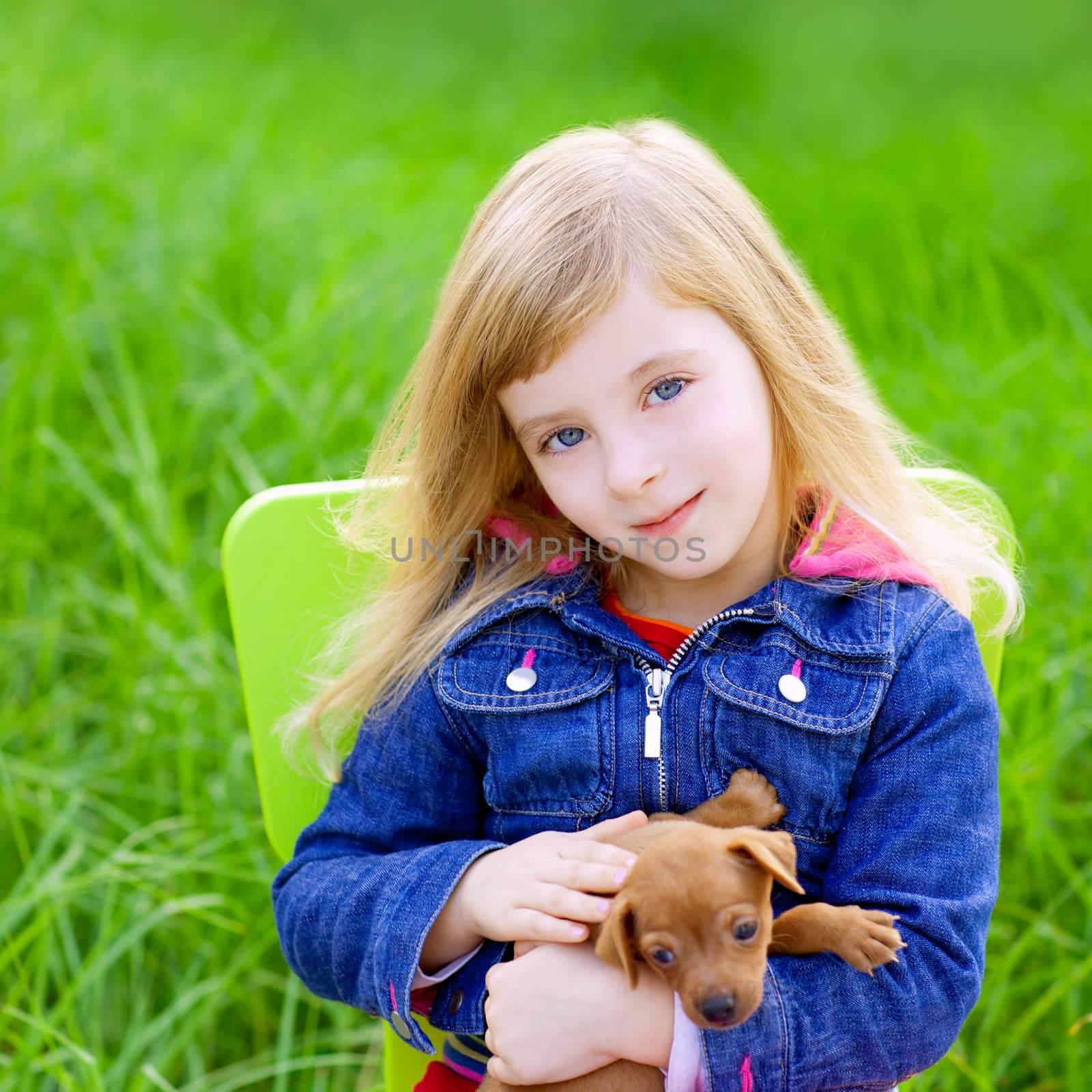 Blond kid girl with puppy pet dog sit in outdoor green grass