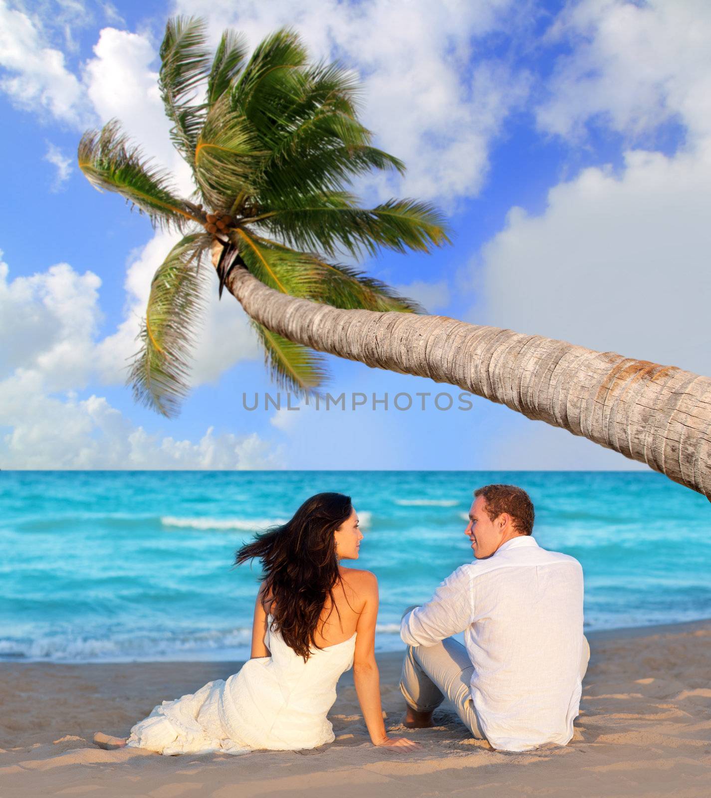 couple in love sitting in blue beach by lunamarina