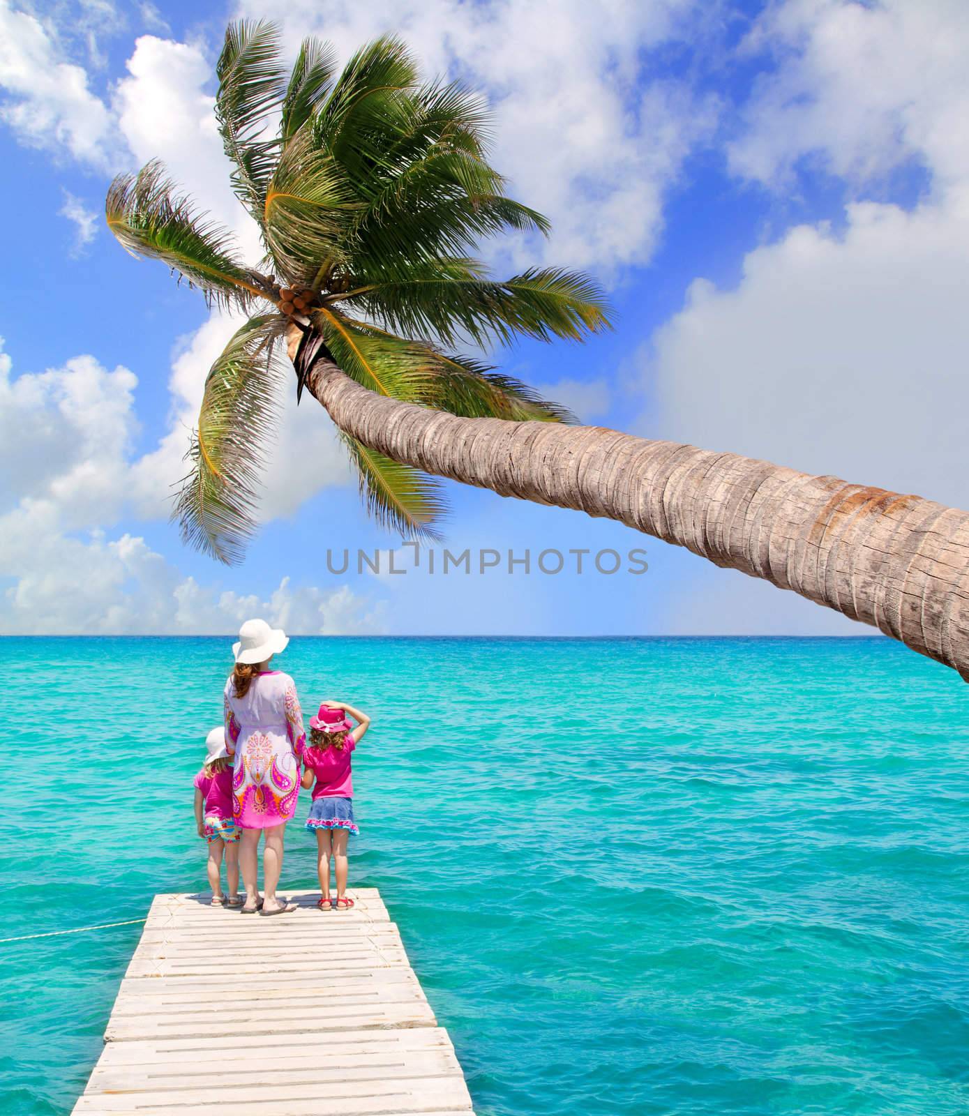 Daughters and mother in jetty on tropical beach by lunamarina