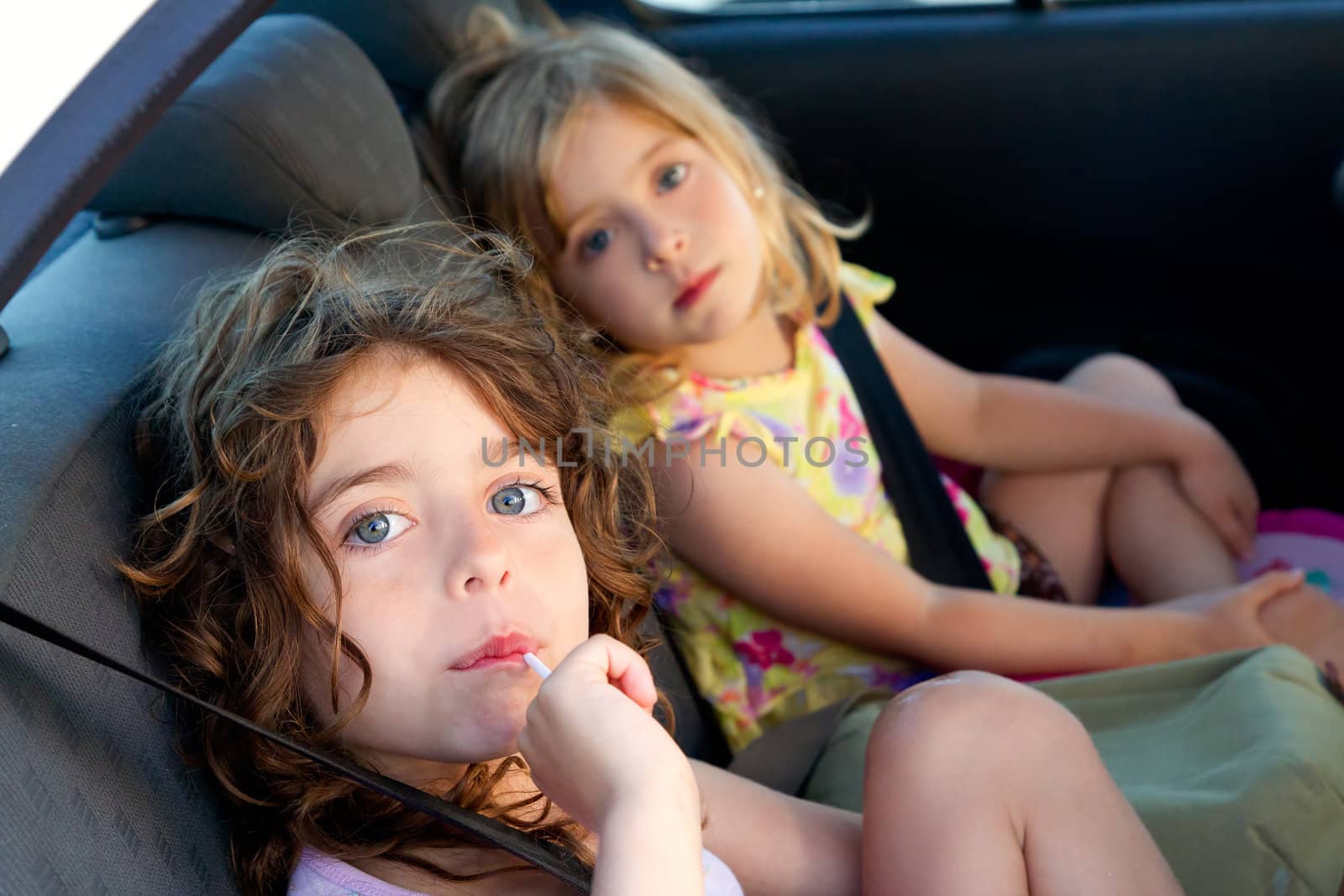 little girls inside car eating candy stick by lunamarina
