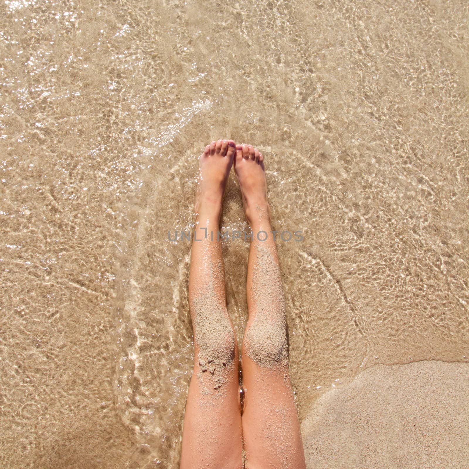 Children girl legs in beach sand shore at summer vacation