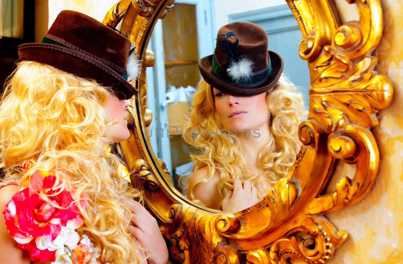 fashion blond woman with hat looking in baroque golden frame mirror