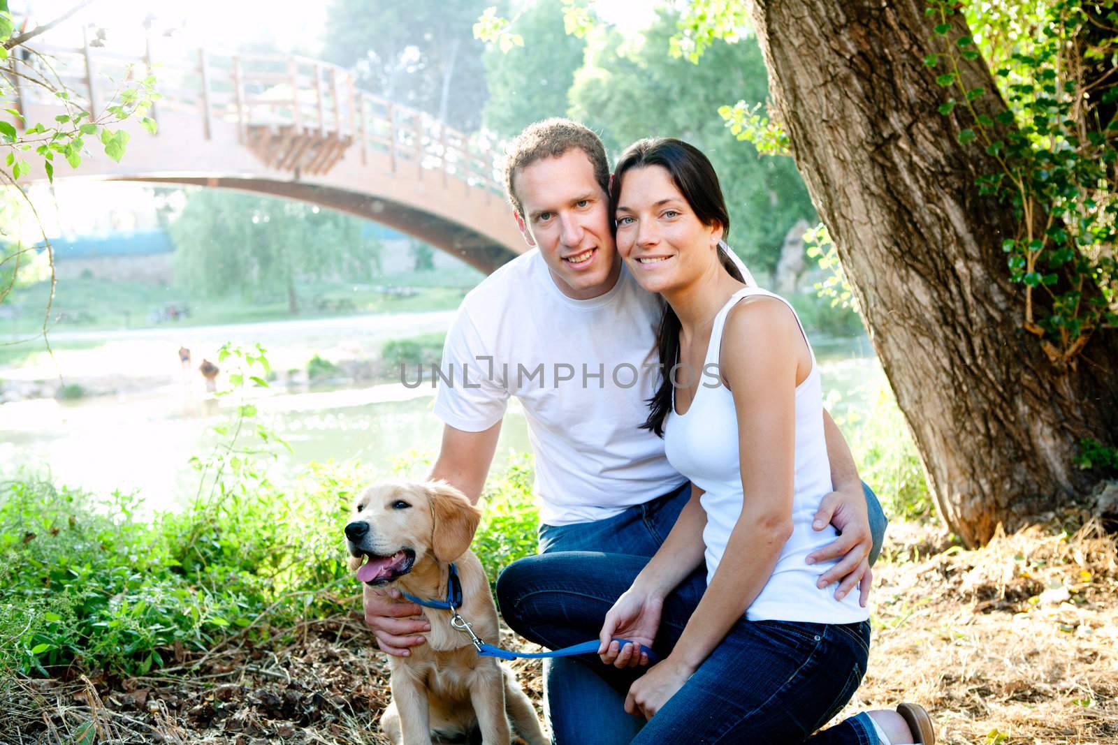 Couple in love with dog in outdoor river with bridge