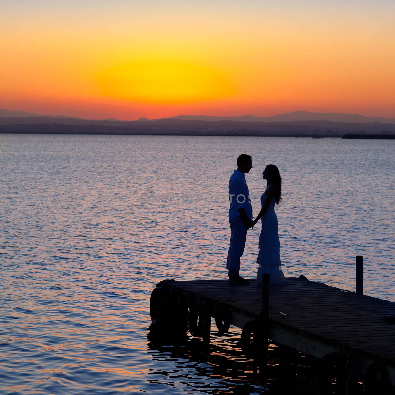 couple in love back light silhouette at lake sunset full length