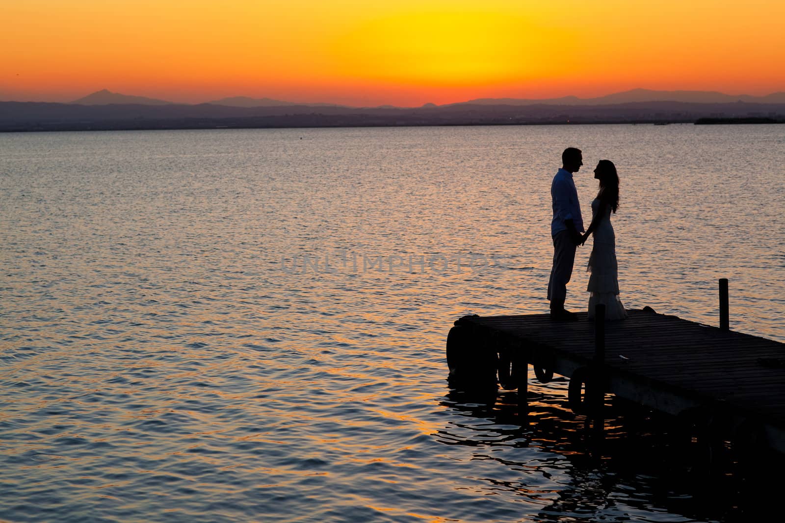 couple sunset profile back light in orange sea full length