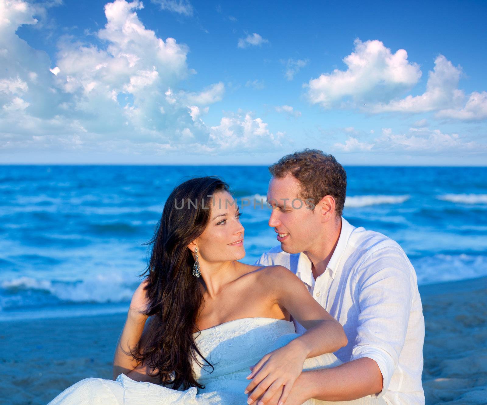 couple in love sitting in blue beach by lunamarina