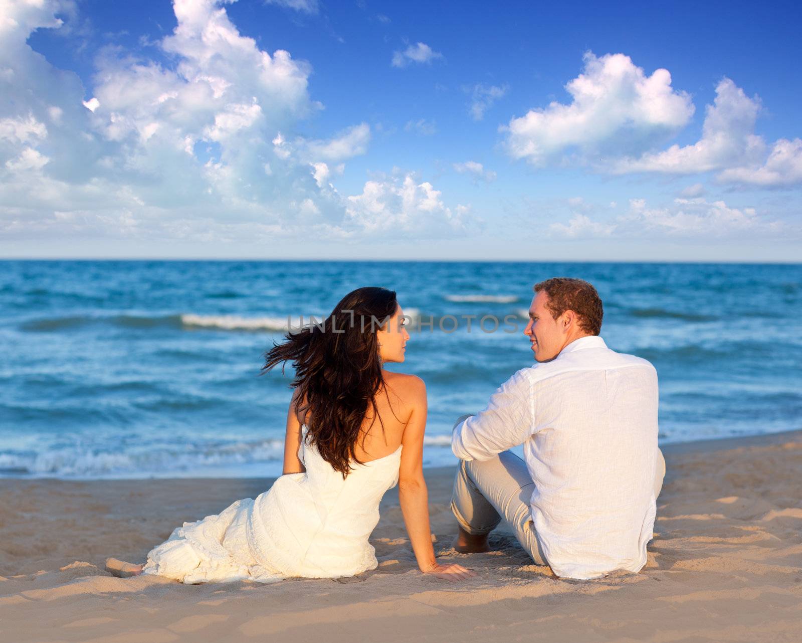 couple in love sitting in blue beach by lunamarina