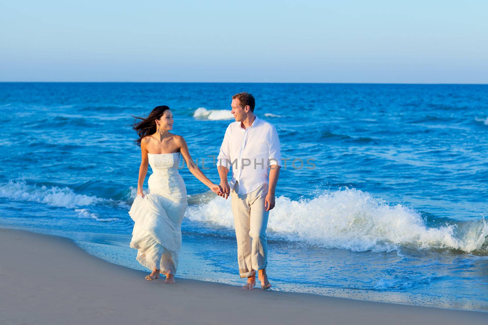 Mediterranean couple walking in blue beach shore