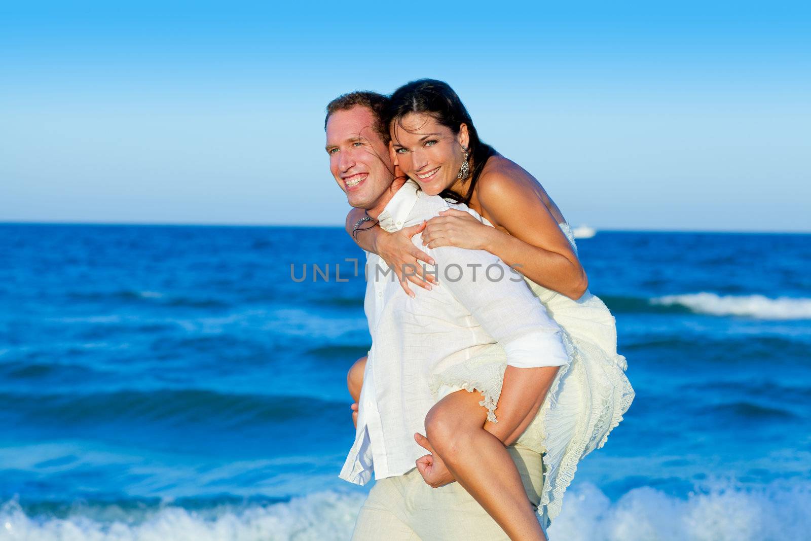 couple in love piggyback playing in beach by lunamarina