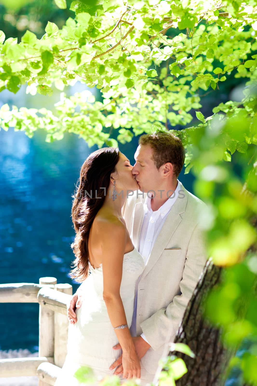 couple in love kissing in forest tree blue lake by lunamarina
