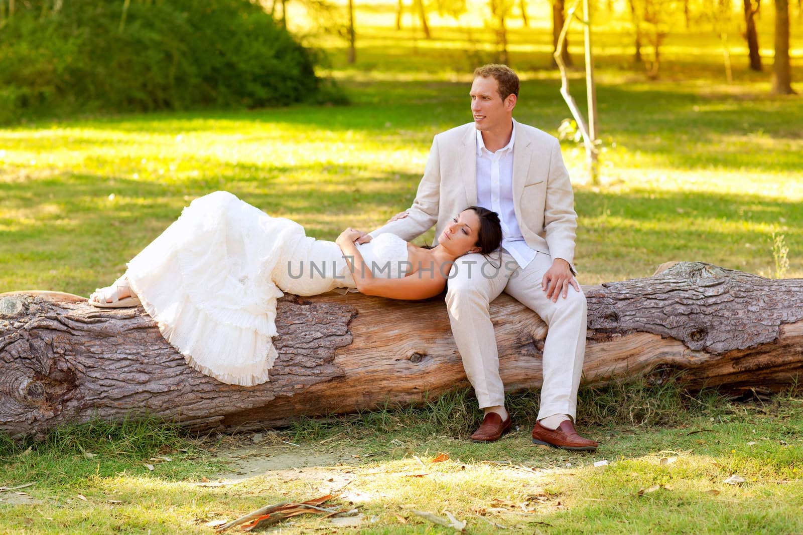 woman lying on husband leg in a park trunk just married