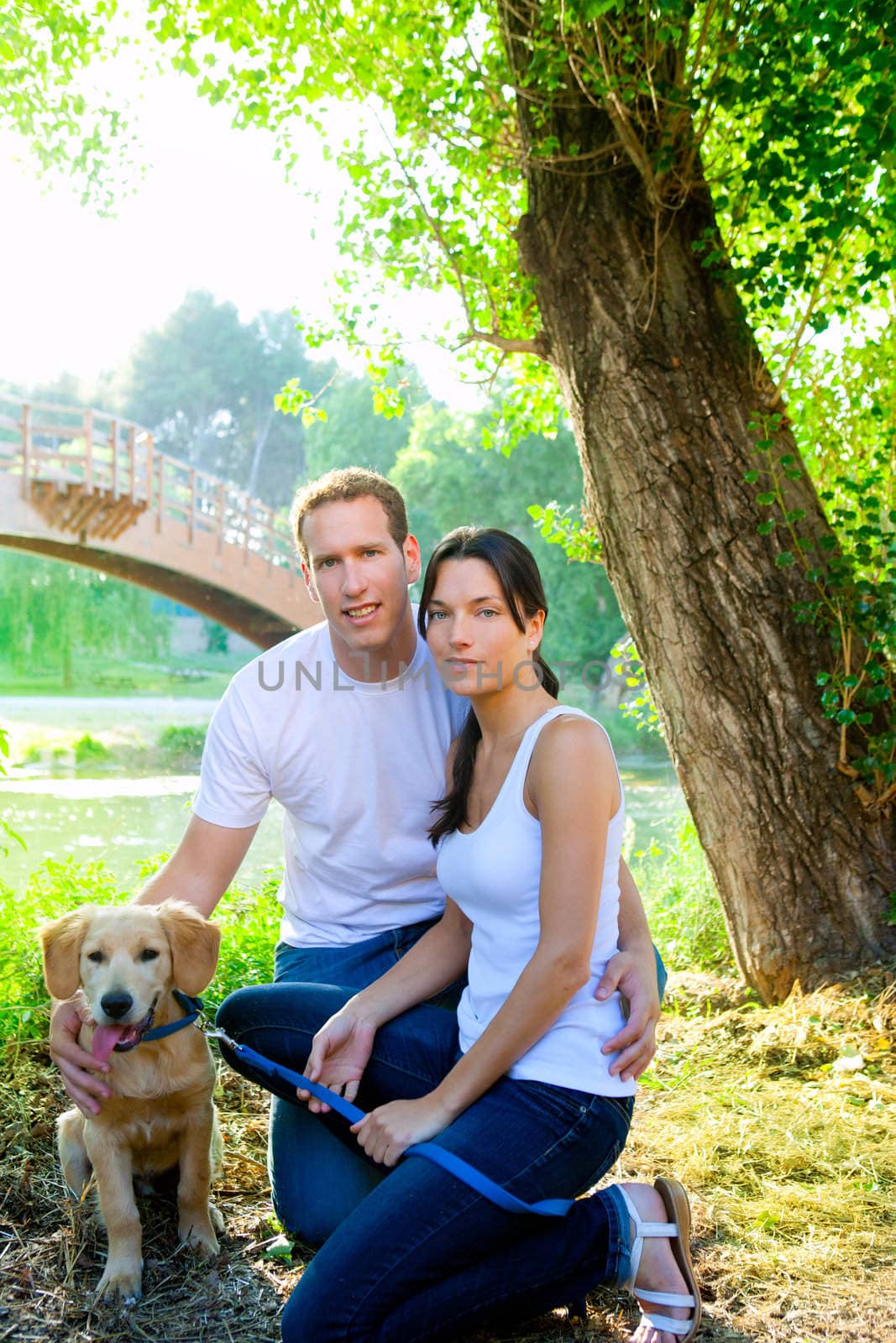couple happy posing with golden retirever dog in outdoor park