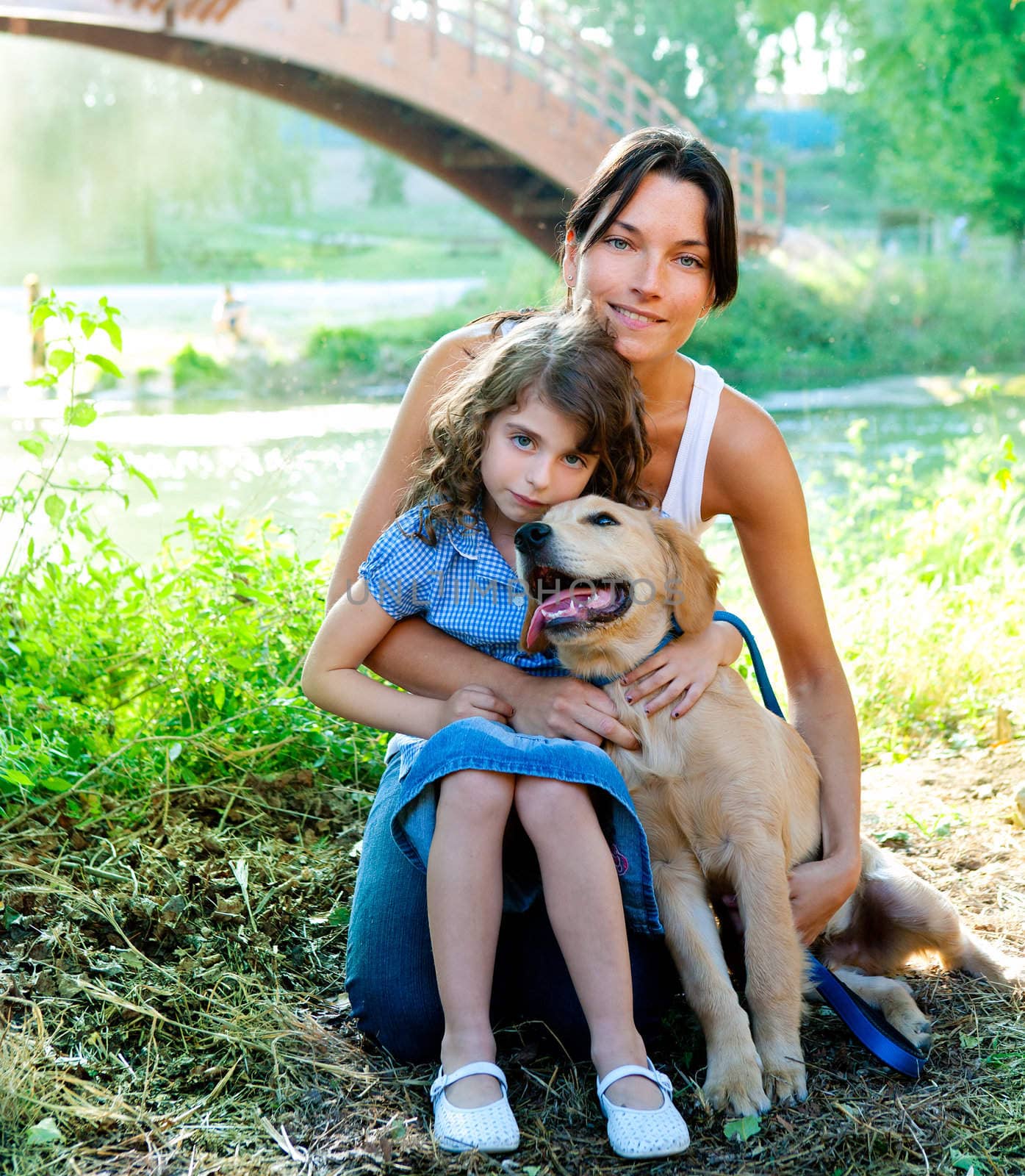 daughter and mother with golden retriever dog in outdoor park