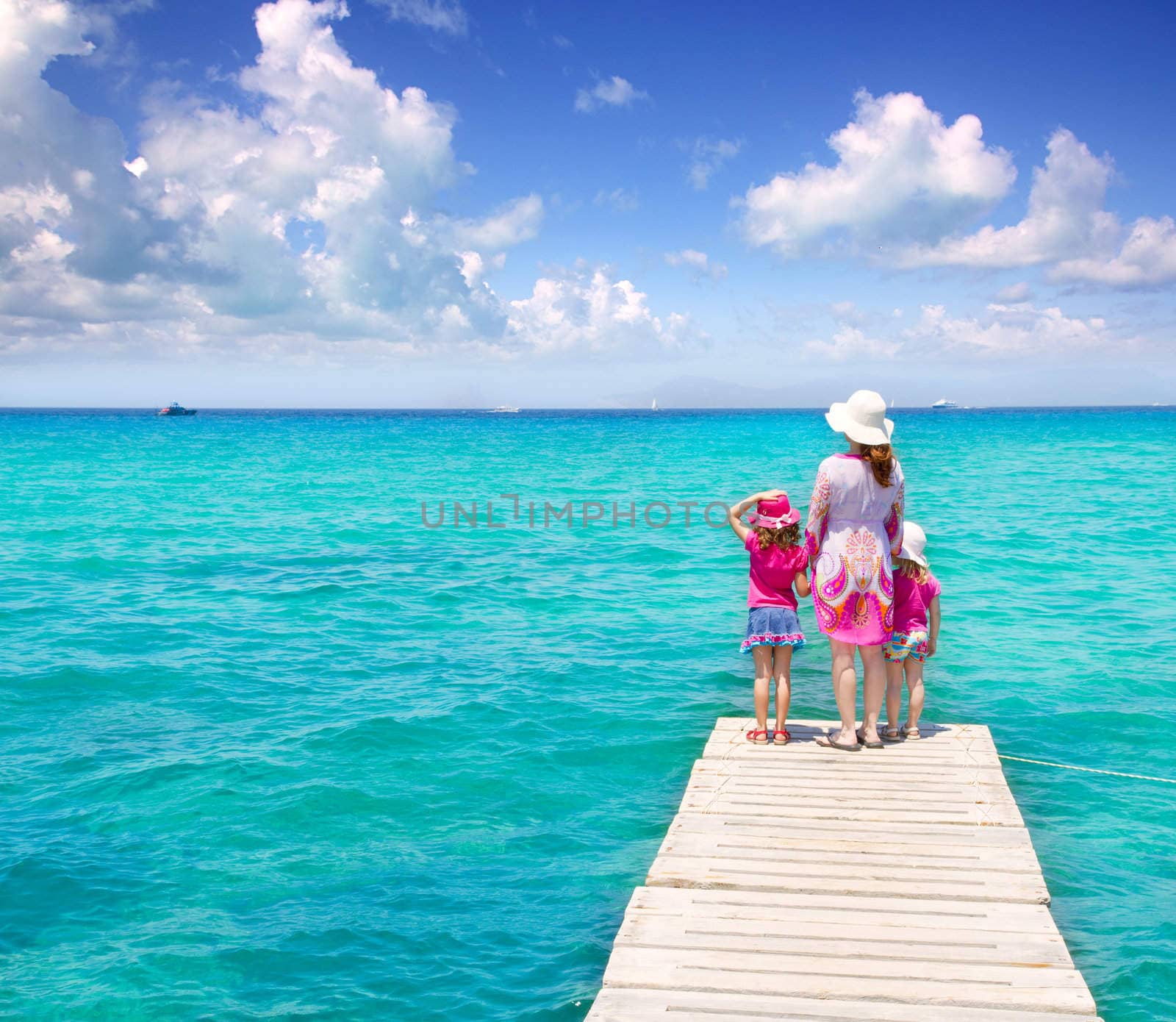 Daughters and mother in jetty on Formentera with turquoise sea