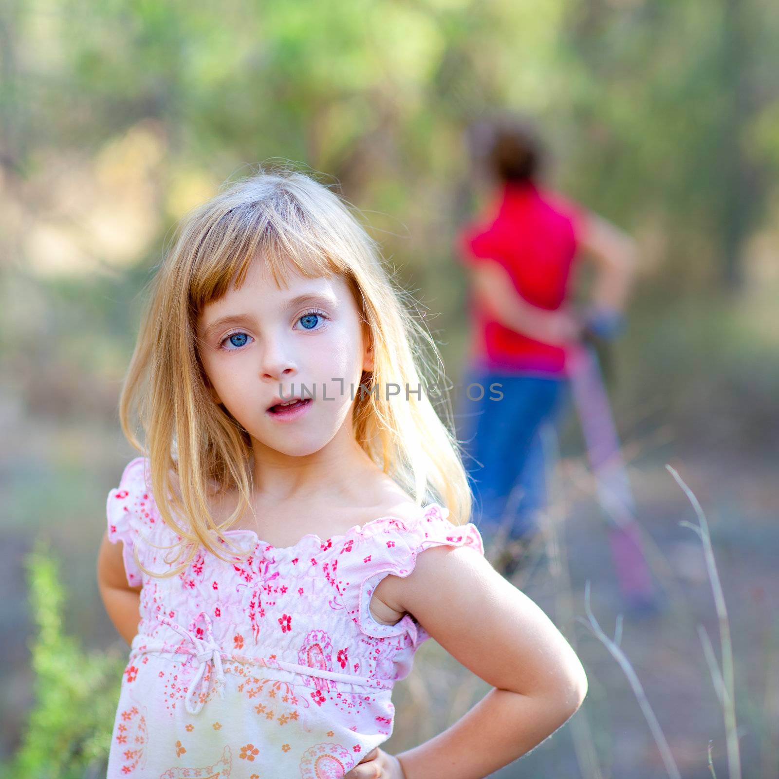 blond kid girl in forest park posing to camera