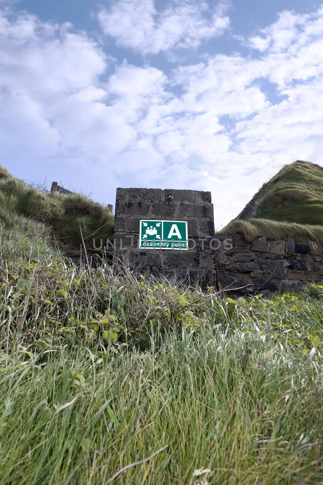 an assembly point sign on a block wall at a beach in Ireland