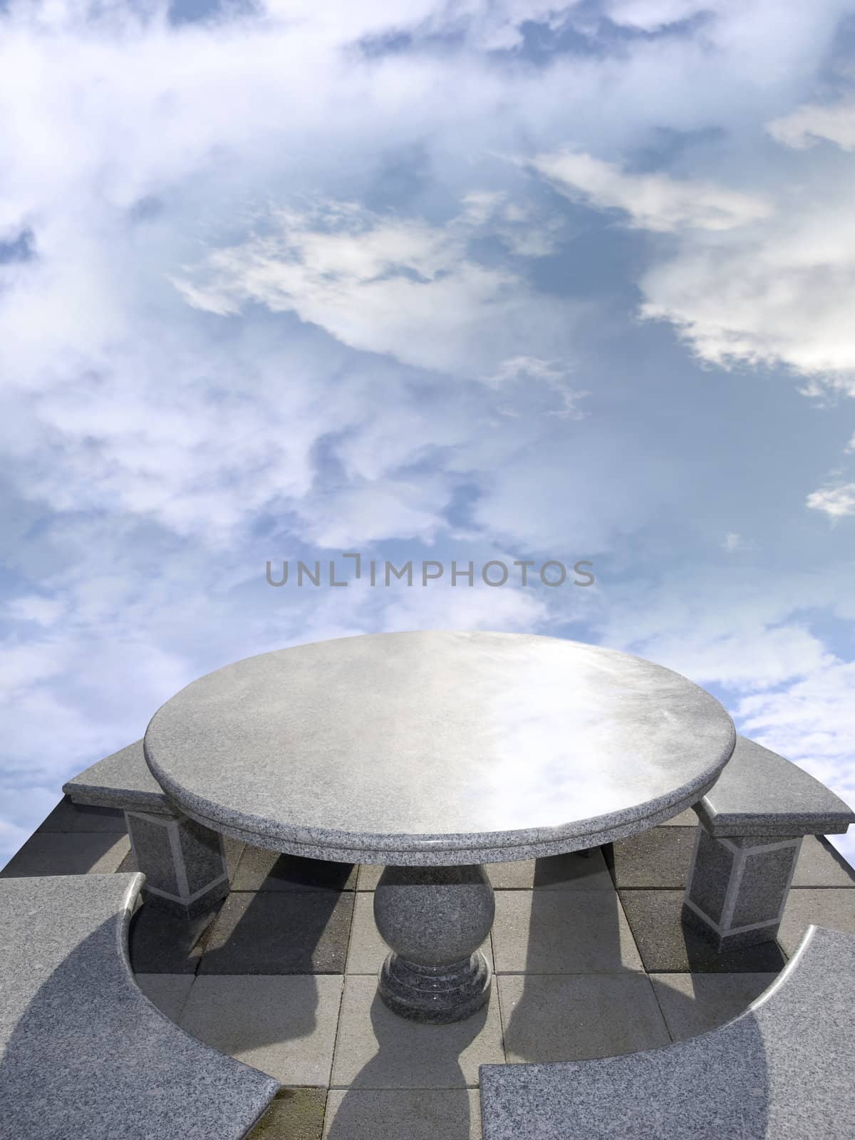 large marble table and chairs against a bright blue cloudy background