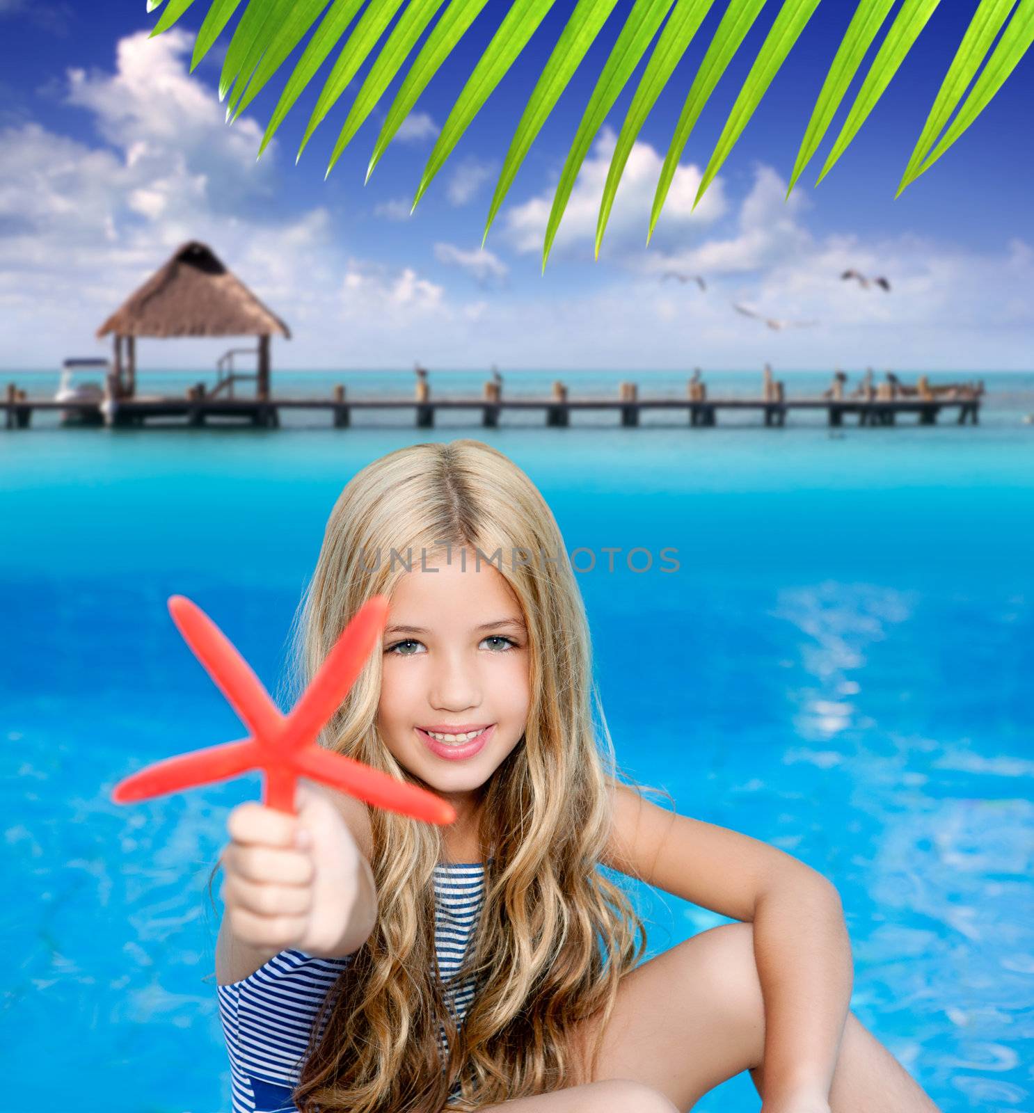 children blond girl in summer vacation tropical beach with starfish