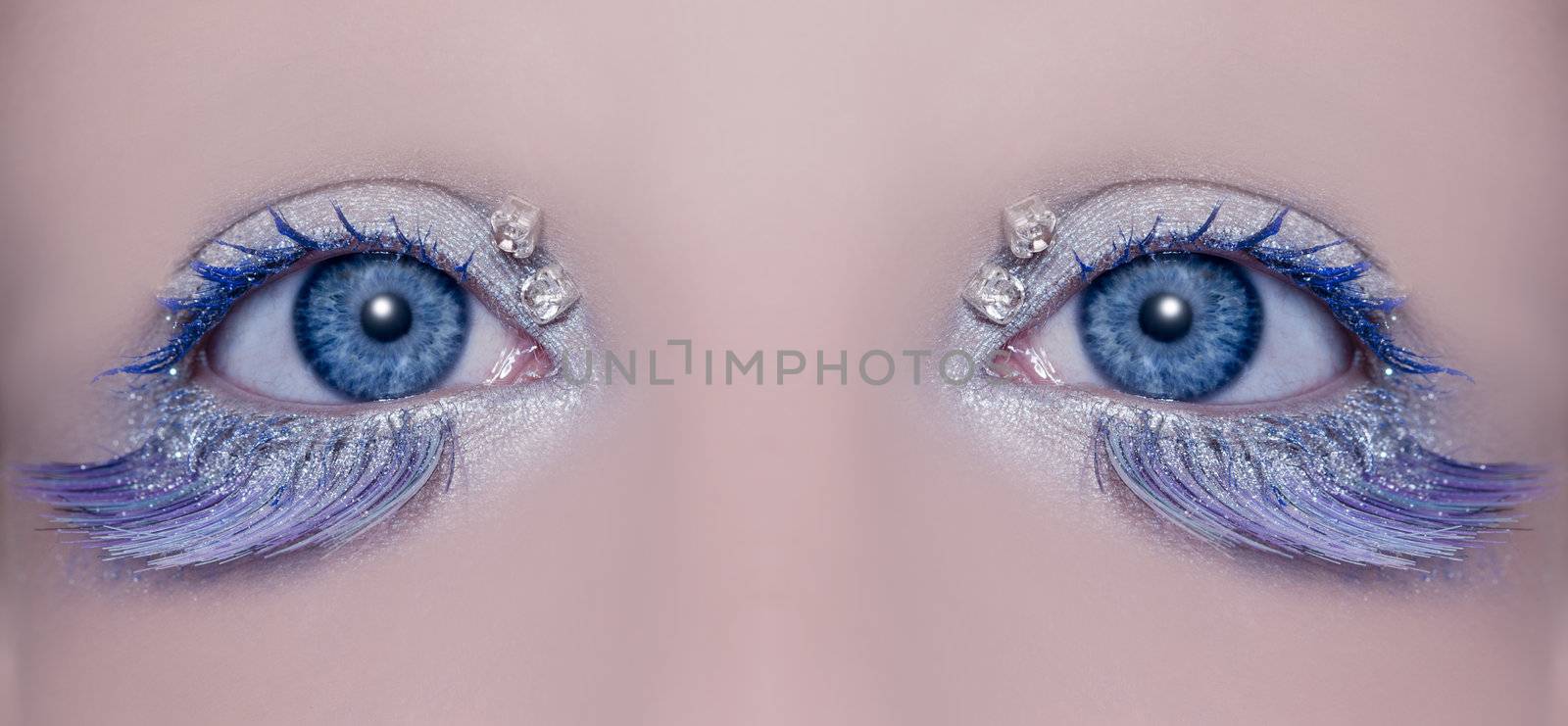 Blue eye macro closeup with a winter inspired silver makeup some jewels and feather eyelashes