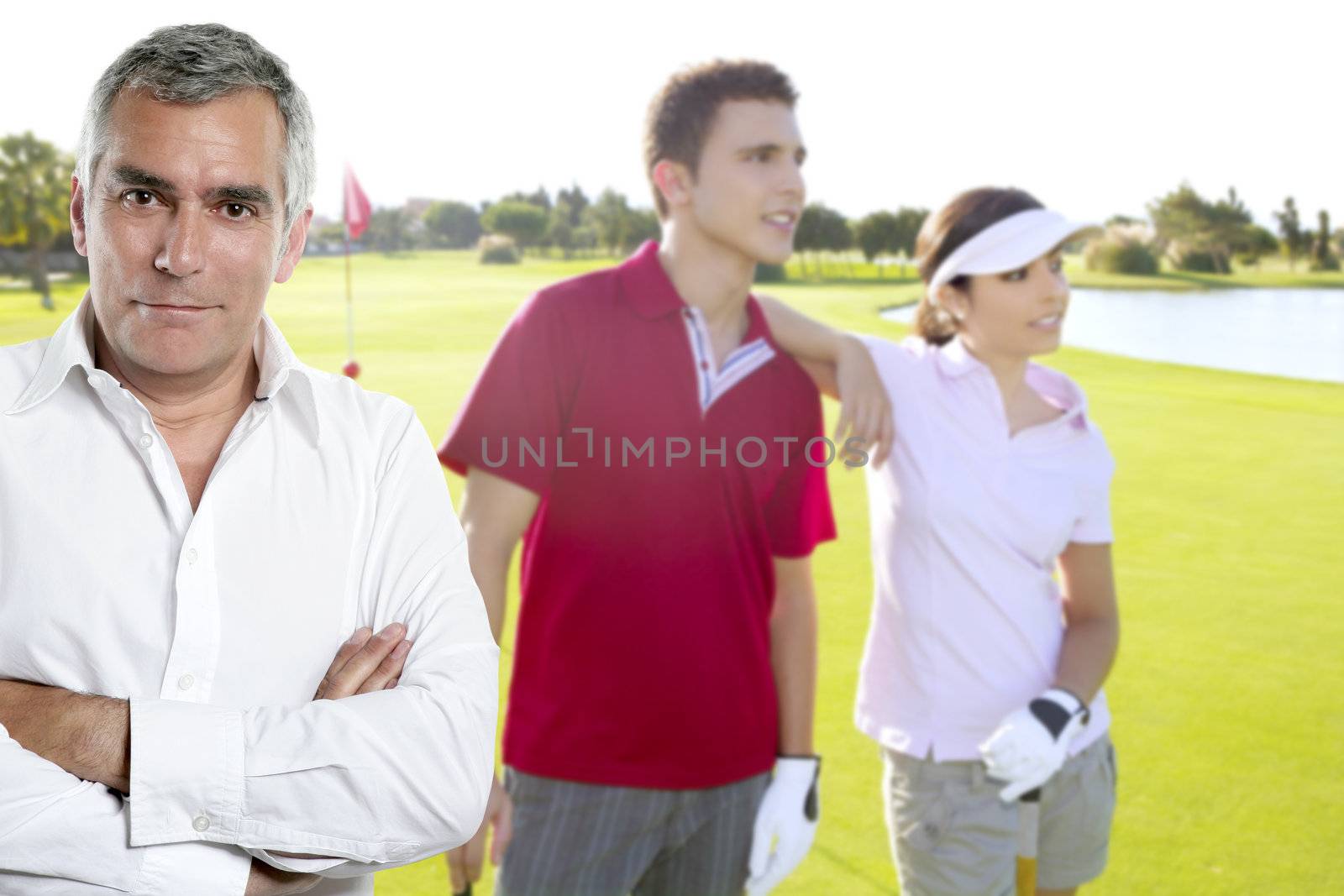 senior golfer man portrait in green course withyoung couple in background