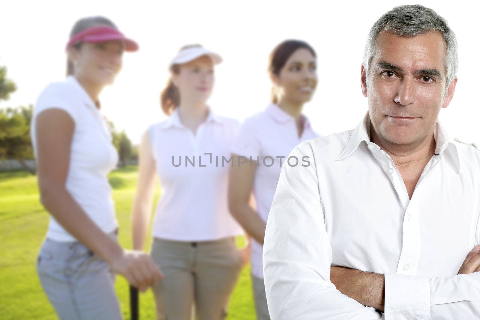 senior golfer man portrait in green course with three women in background