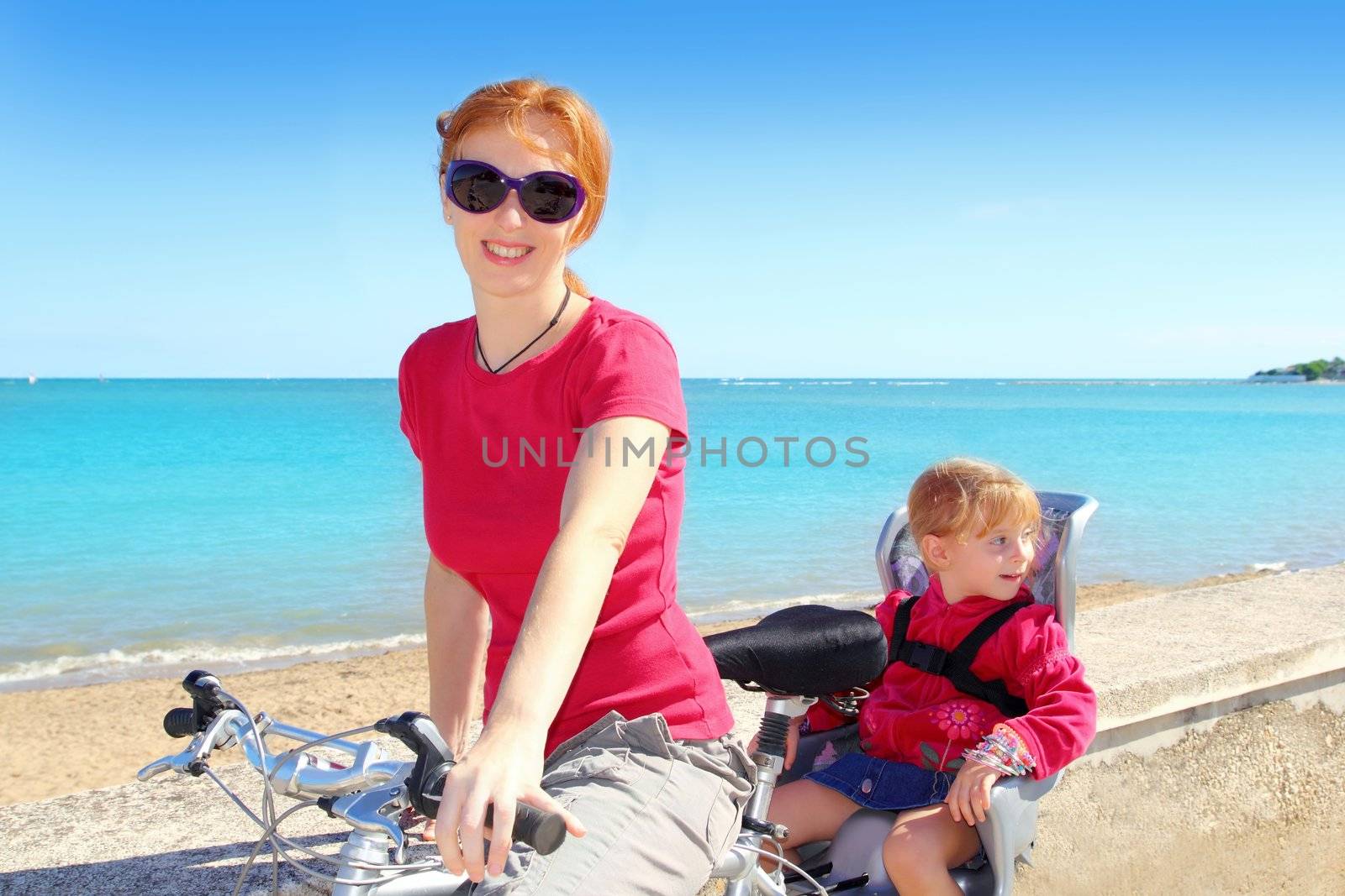 daughter and mother on bicycle in beach sea by lunamarina