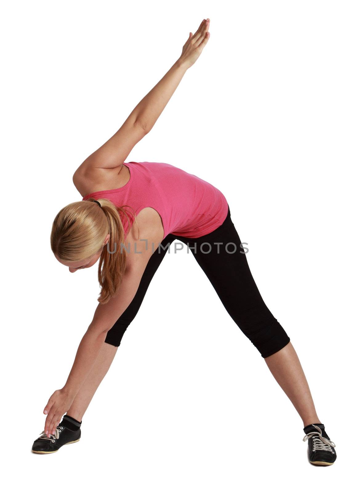 Blond woman standing with legs apart bending down with one hand touching one foot and the other raised up, against a white background.