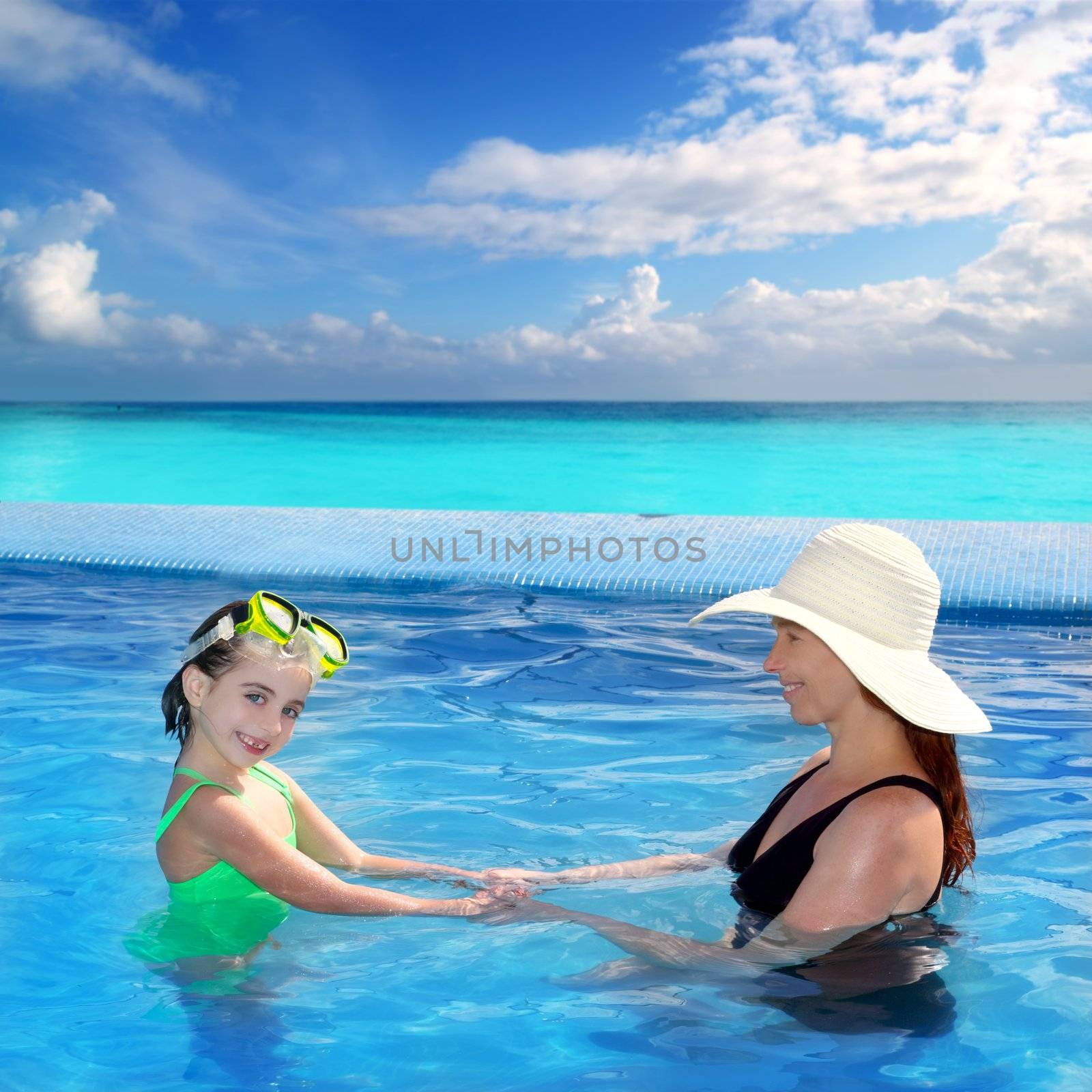 daughter and mother in swimming pool with direct view to a tropical Caribbean beach