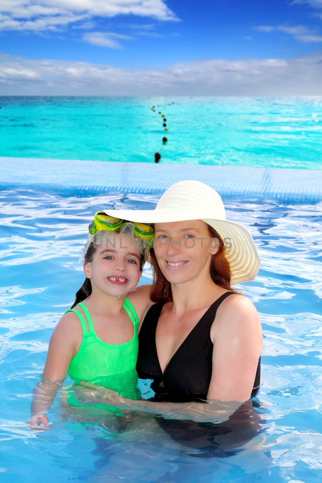 mother and daughter hug in a pool with direct view to Caribbean tropical beach