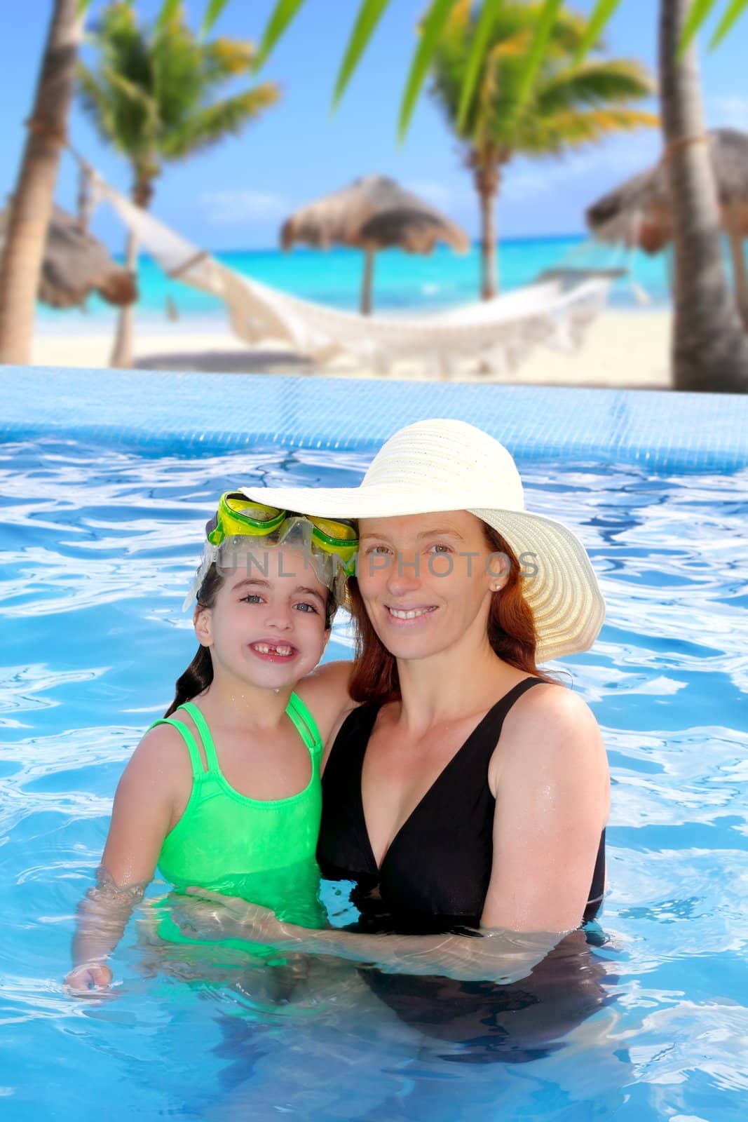 mother and daughter hug in a pool with direct view to Caribbean tropical beach