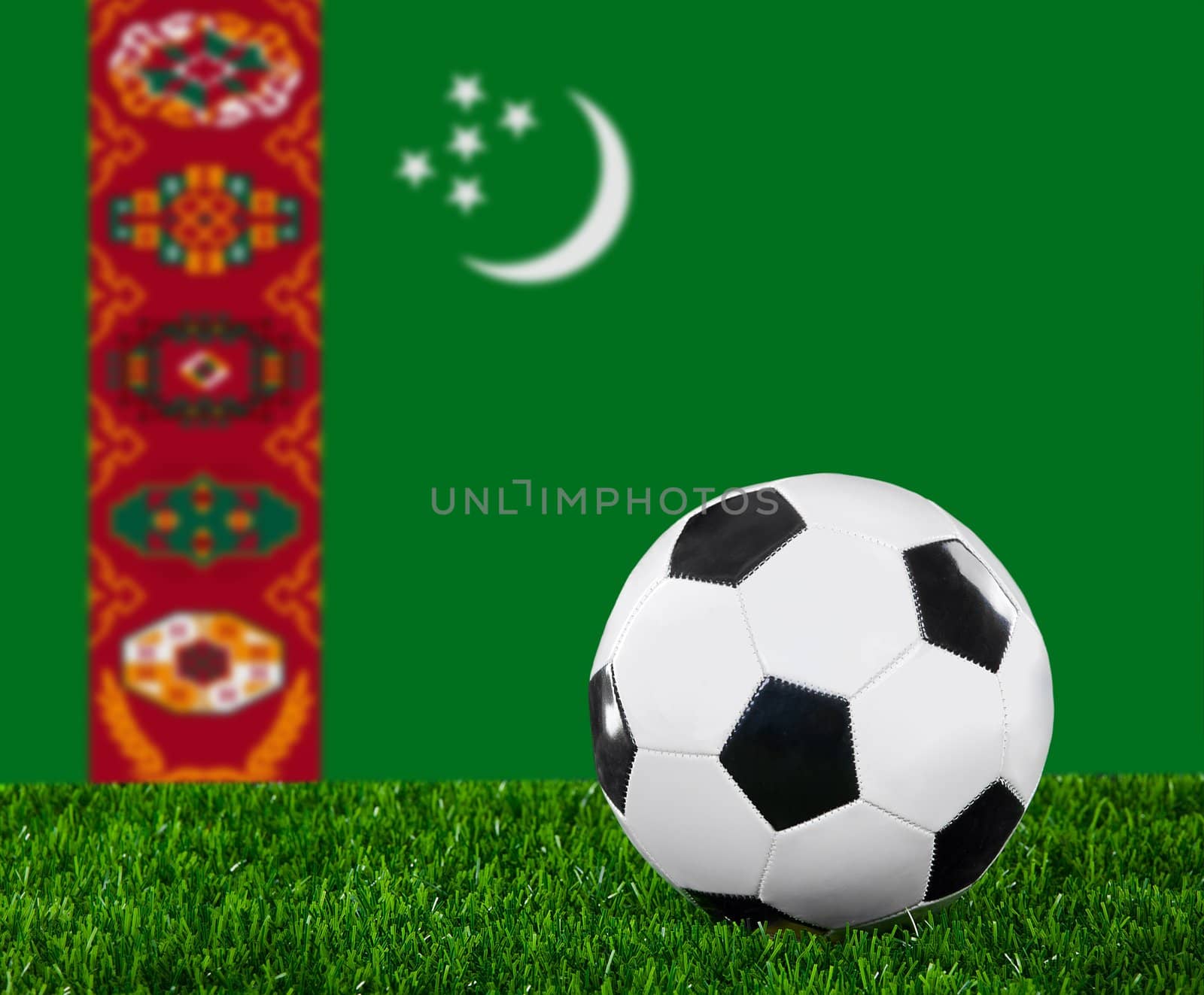 The Turkmen flag and soccer ball on the green grass
