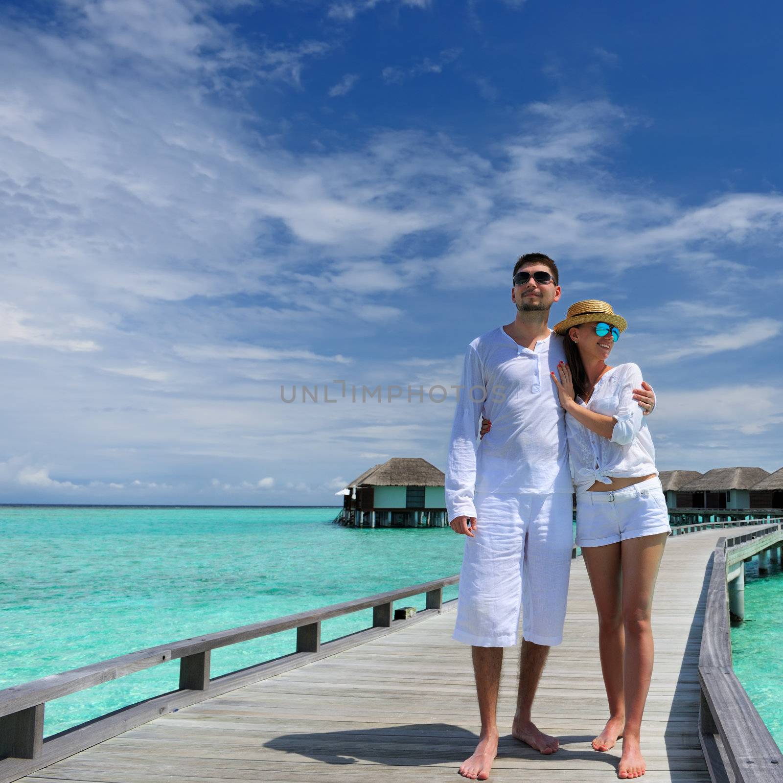 Couple on a beach jetty at Maldives by haveseen