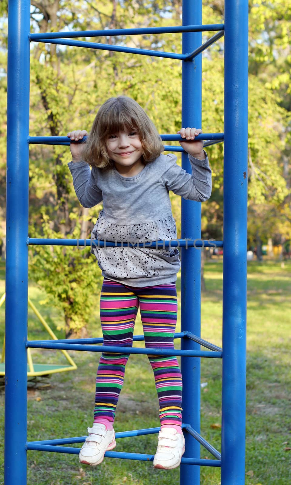 happy little girl climb on park playground by goce