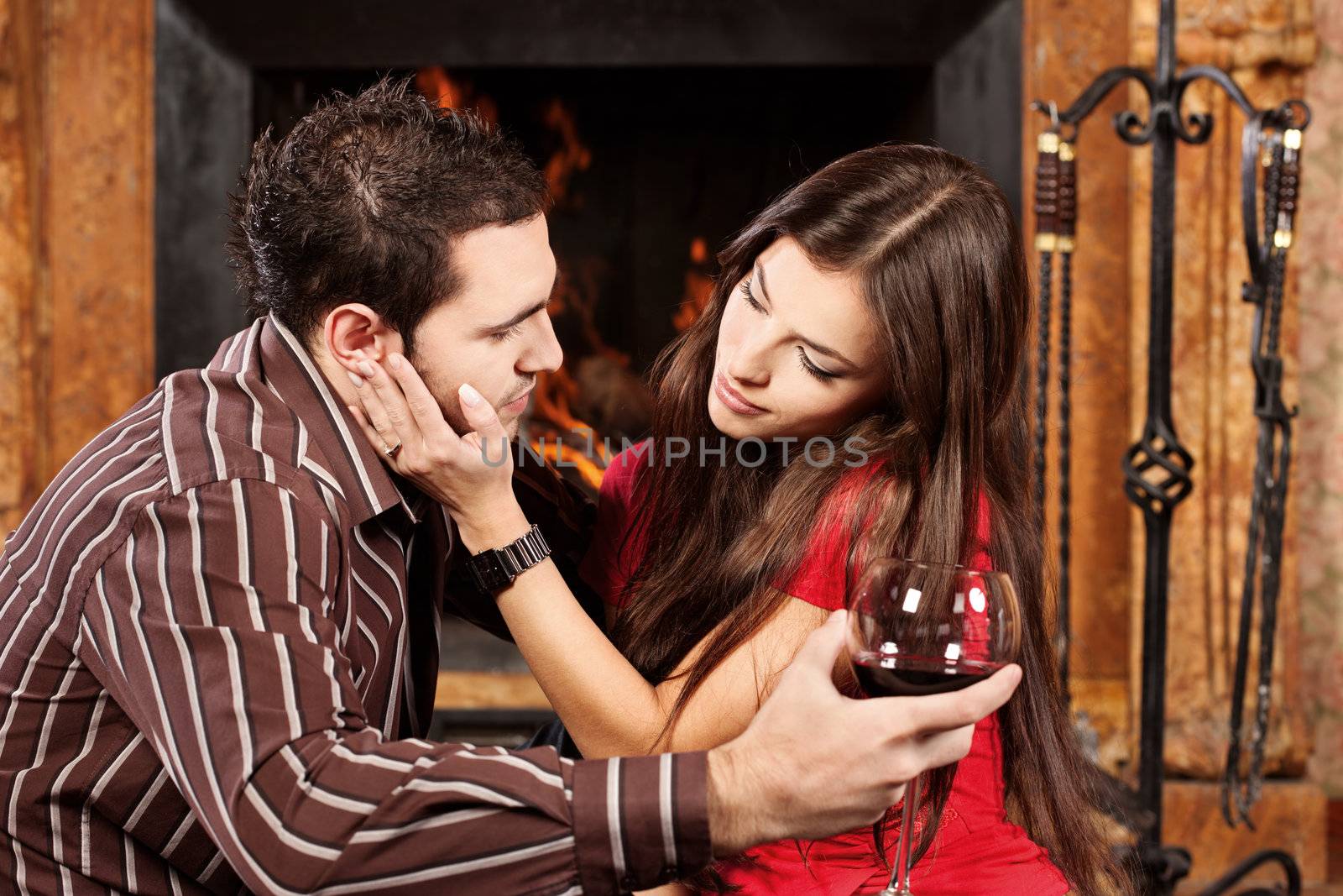 Pretty woman caress her man near fireplace