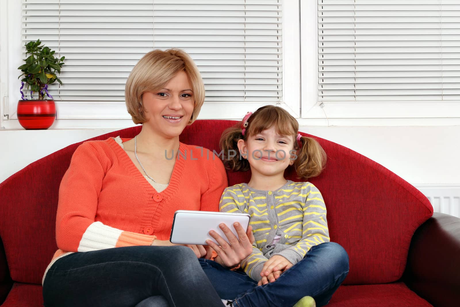 happy mother and daughter sitting on bed with tablet pc by goce