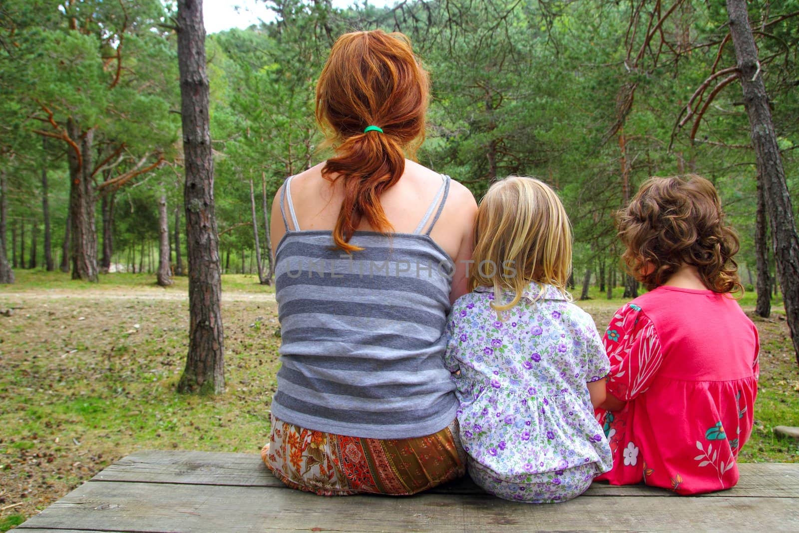 mother and daughters sitting back looking nature park forest wooden bench table