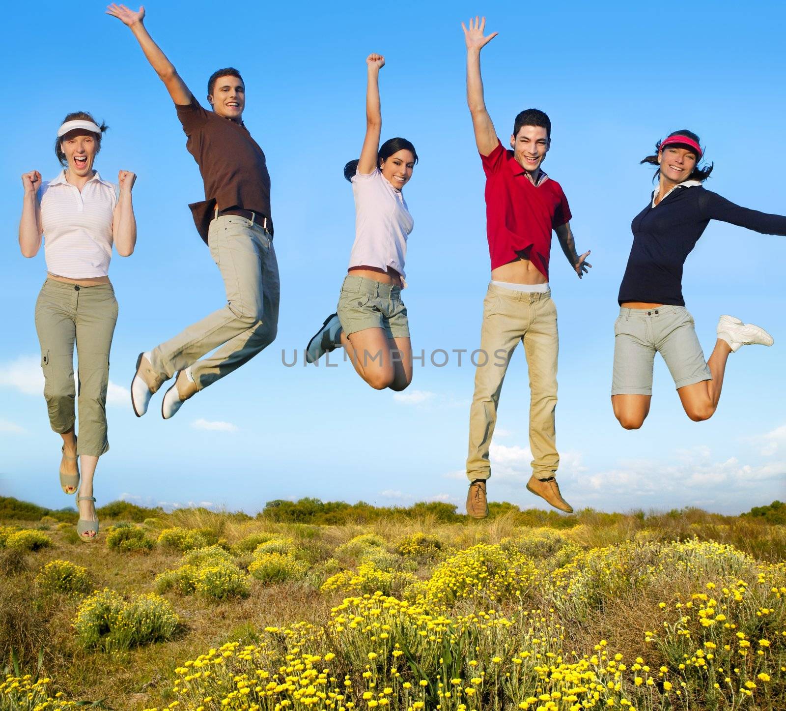 Jumping young people happy group in yellow flowers field