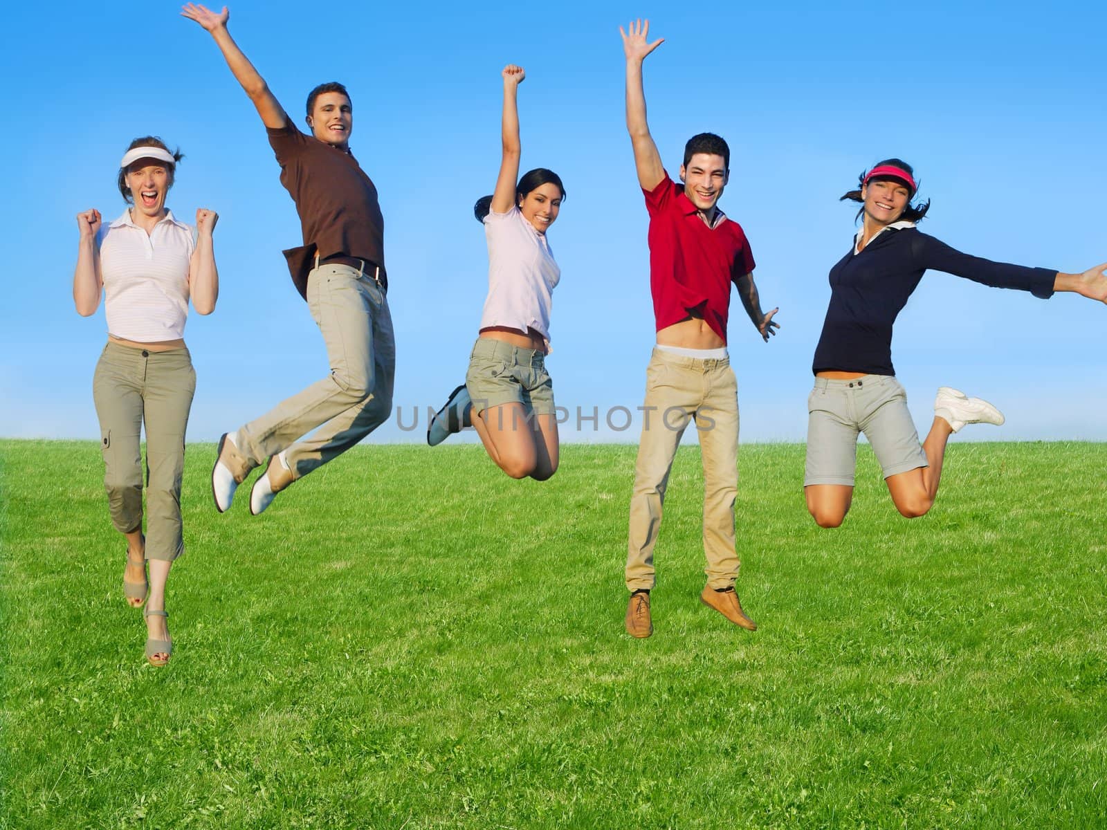 Jumping young people happy group in meadow blue sky outdoor