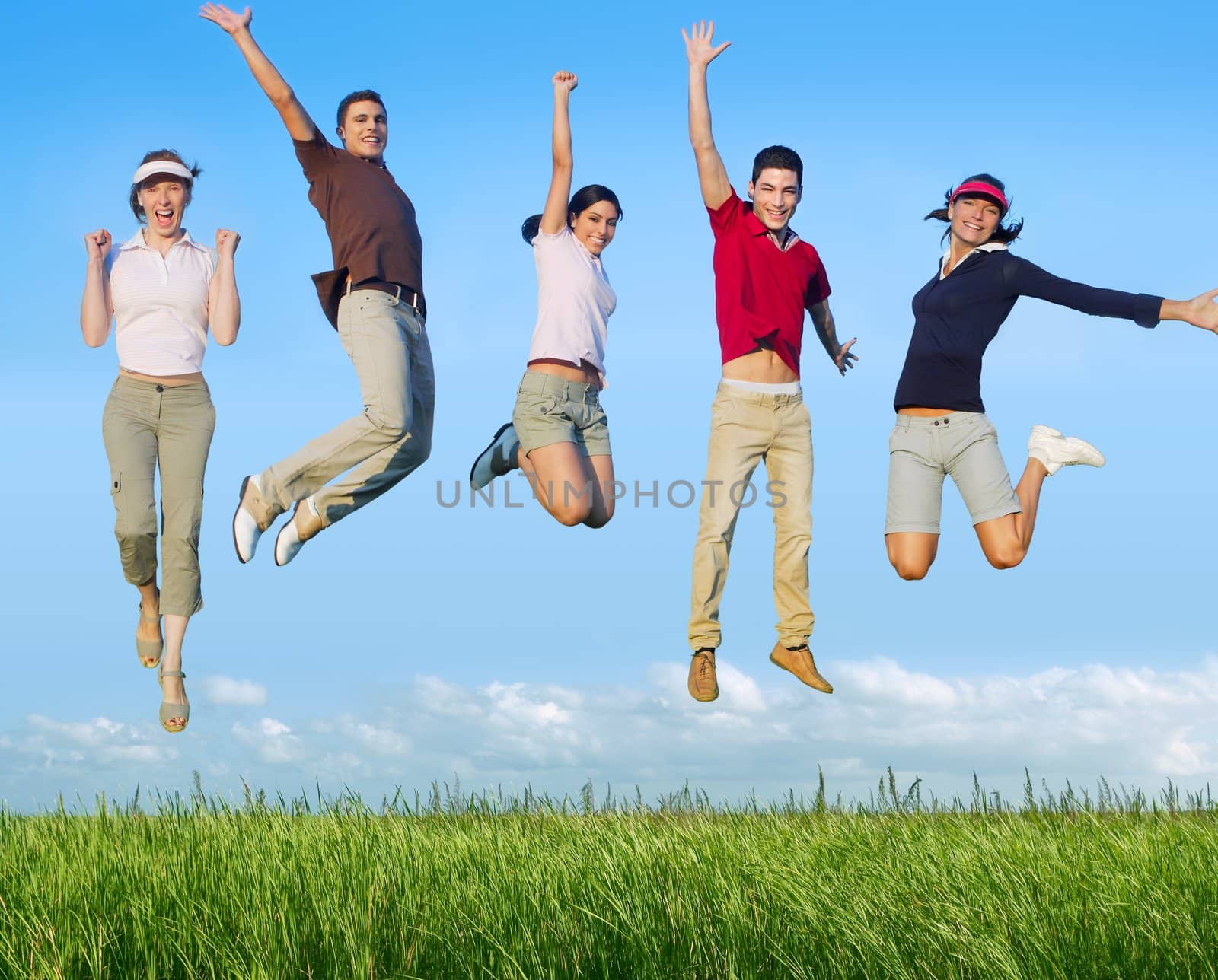 Jumping young people happy group in meadow blue sky outdoor