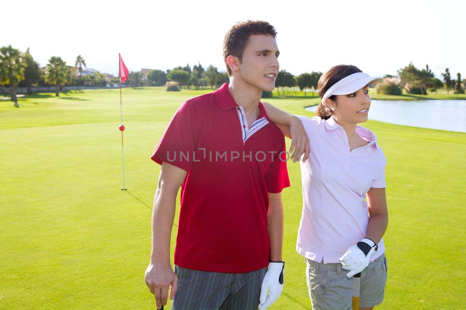 Golf course young happy players couple stand up posing on green