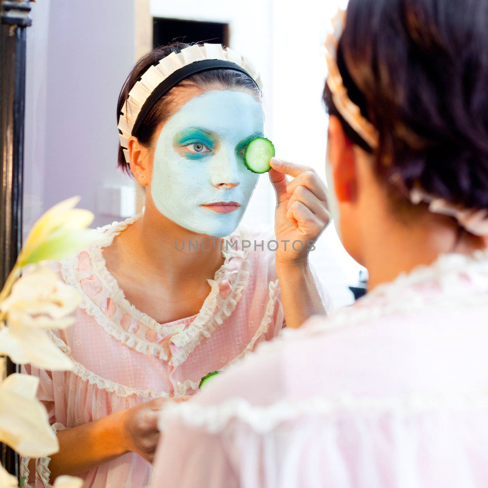Funny housewife beauty green clay mask and cucumber at the mirror