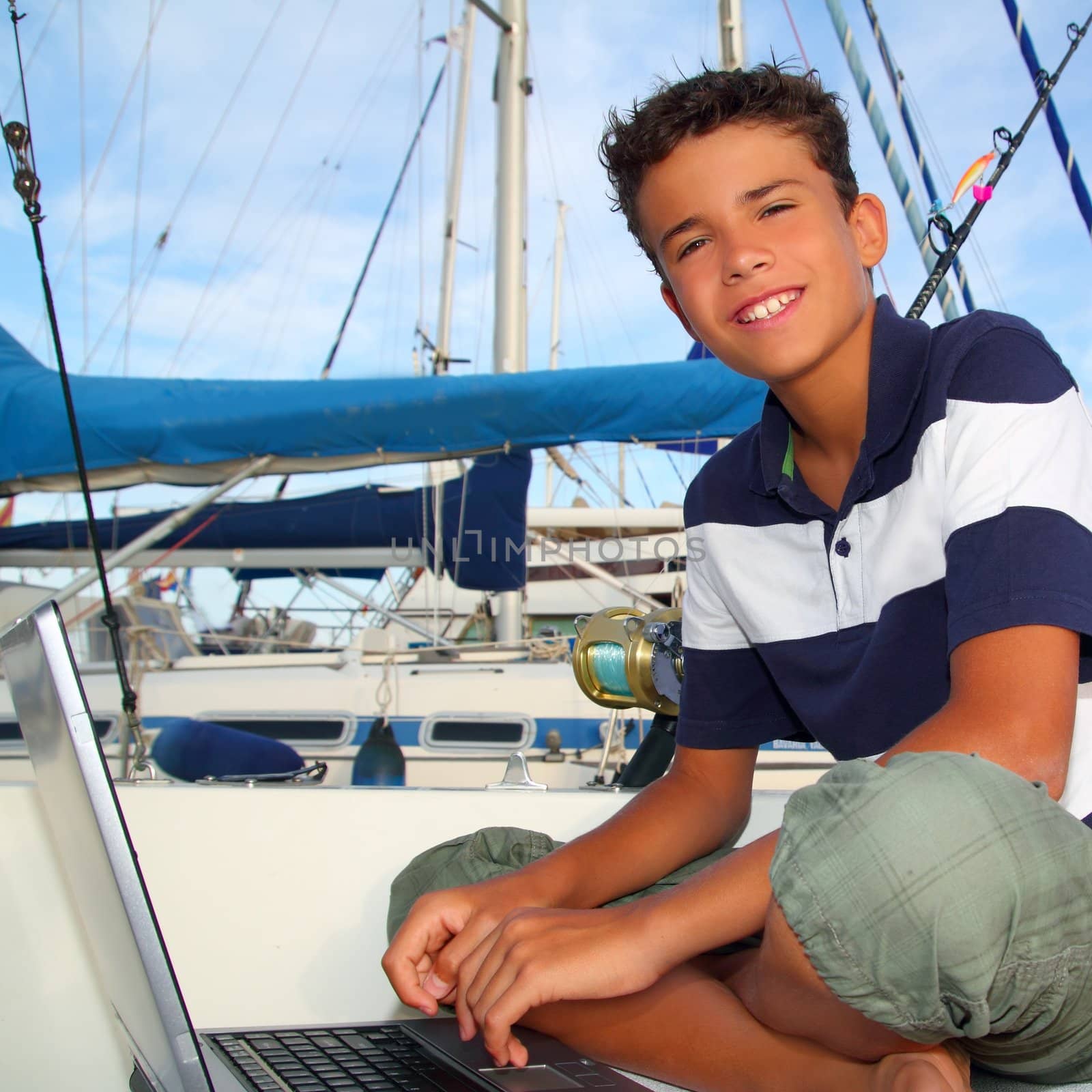 boy teen seat on boat marina laptop computer by lunamarina