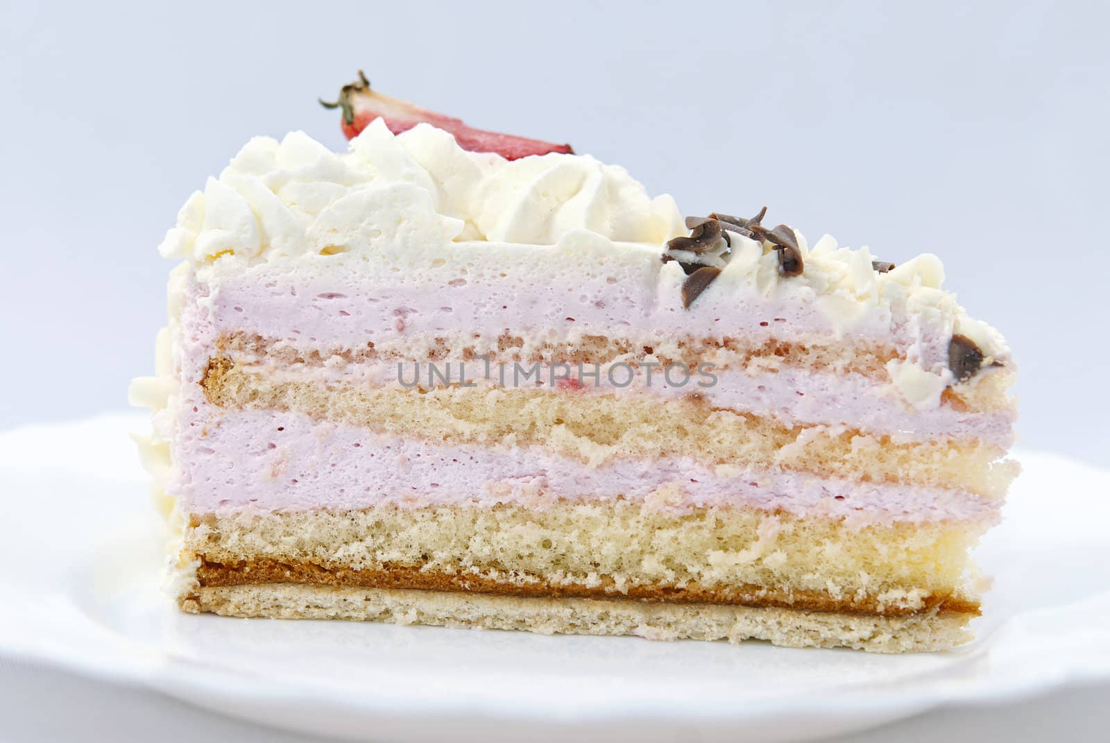 Slice of strawberry cream cake on the white plate