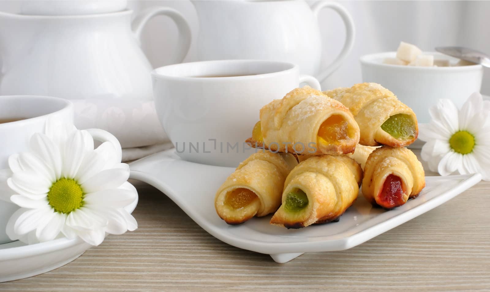 A cup of tea with homemade croissants filled with colorful jelly