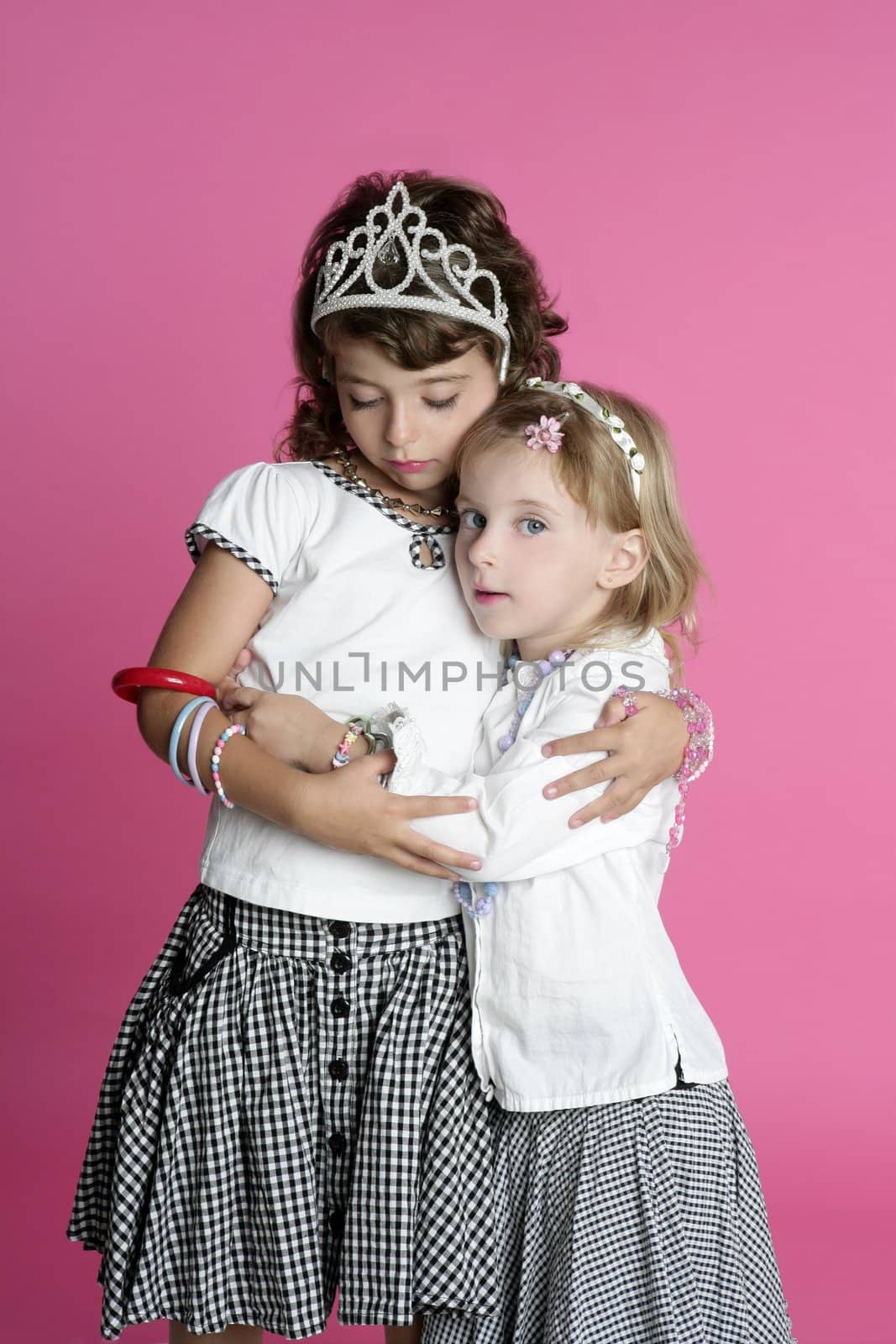 two sisters little girl friends hug stand on pink background